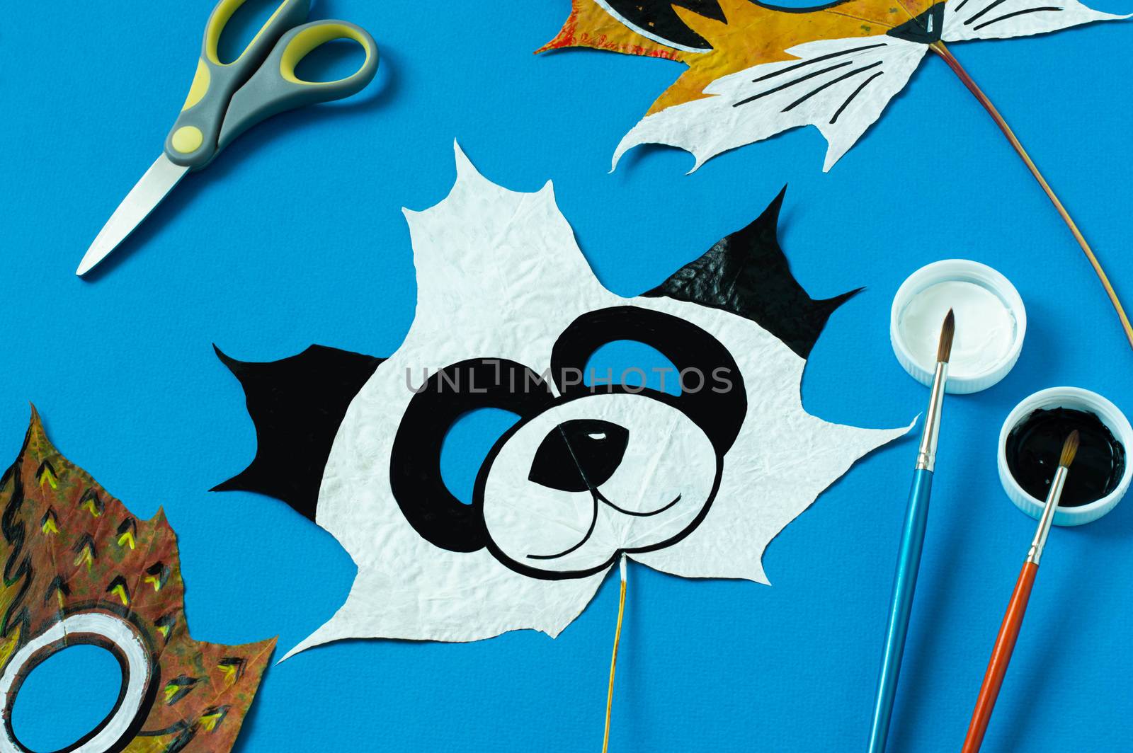 Mask painted on maple leaf. Drawing on autumn leaves. Panda mask for kids autumn carnival or party. Art project for children. DIY concept