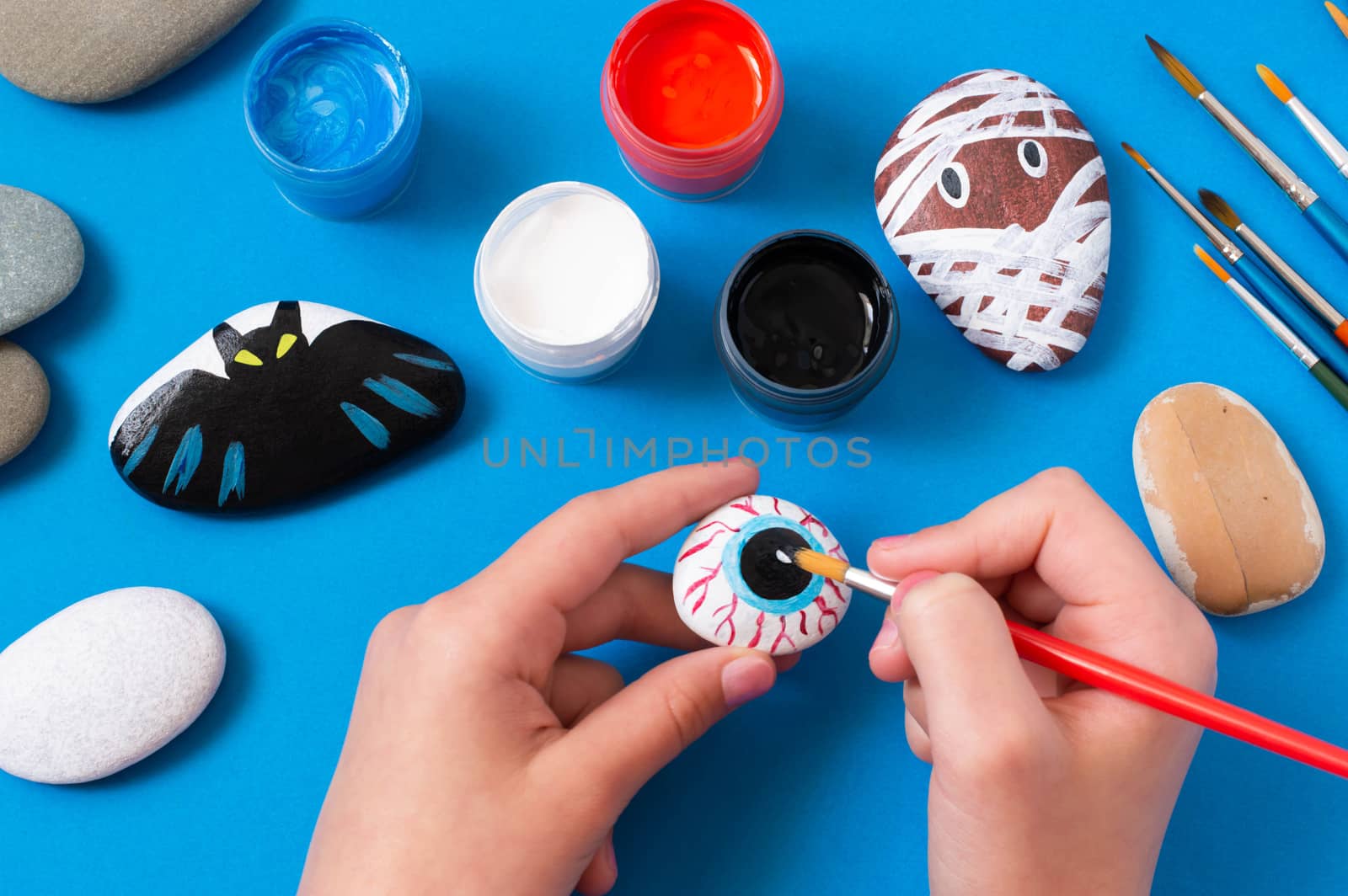 Drawing on stones Halloween characters. Art project for children. DIY concept. Halloween party decor. Eye drawn on sea stone 