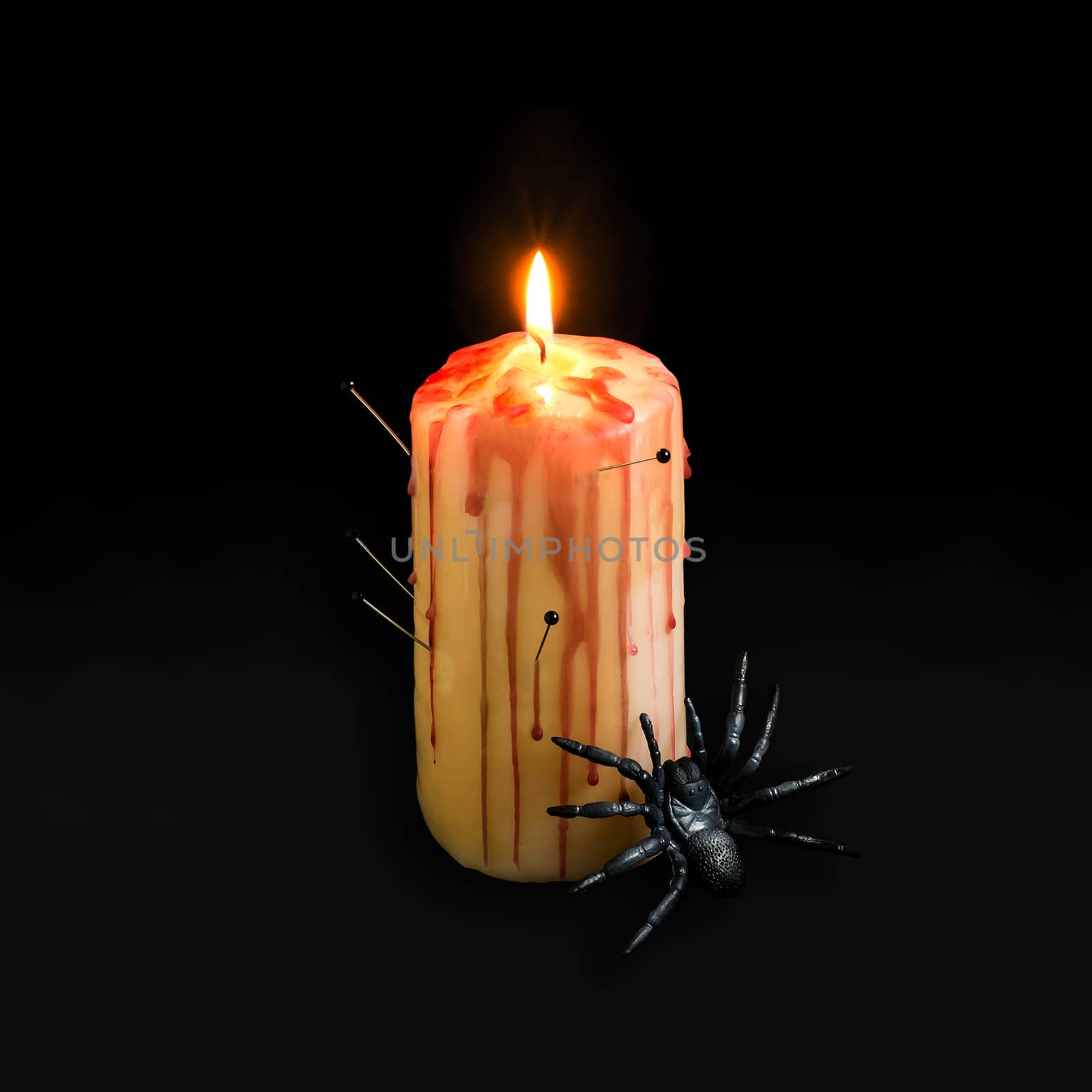 Homemade decor for Halloween. Candle pierced with needles with red brooks and drops like blood and spider on black background. Minimal style. Original design