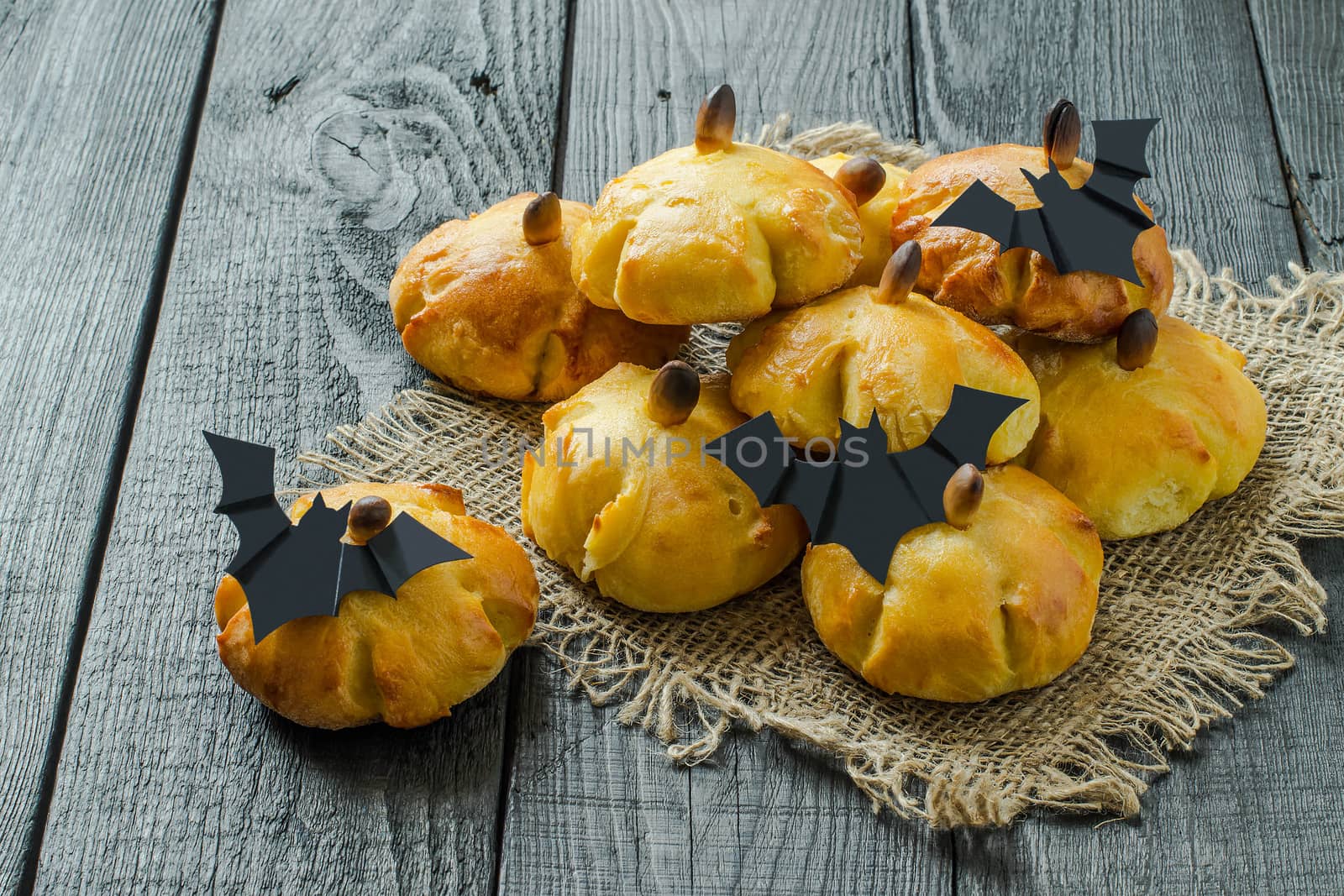 Homemade sweet pumpkin buns. Original baking in form of pumpkin and bats made of paper. Symbols and characters Halloween. Idea of design meal for Halloween party. Scary and funny Halloween food