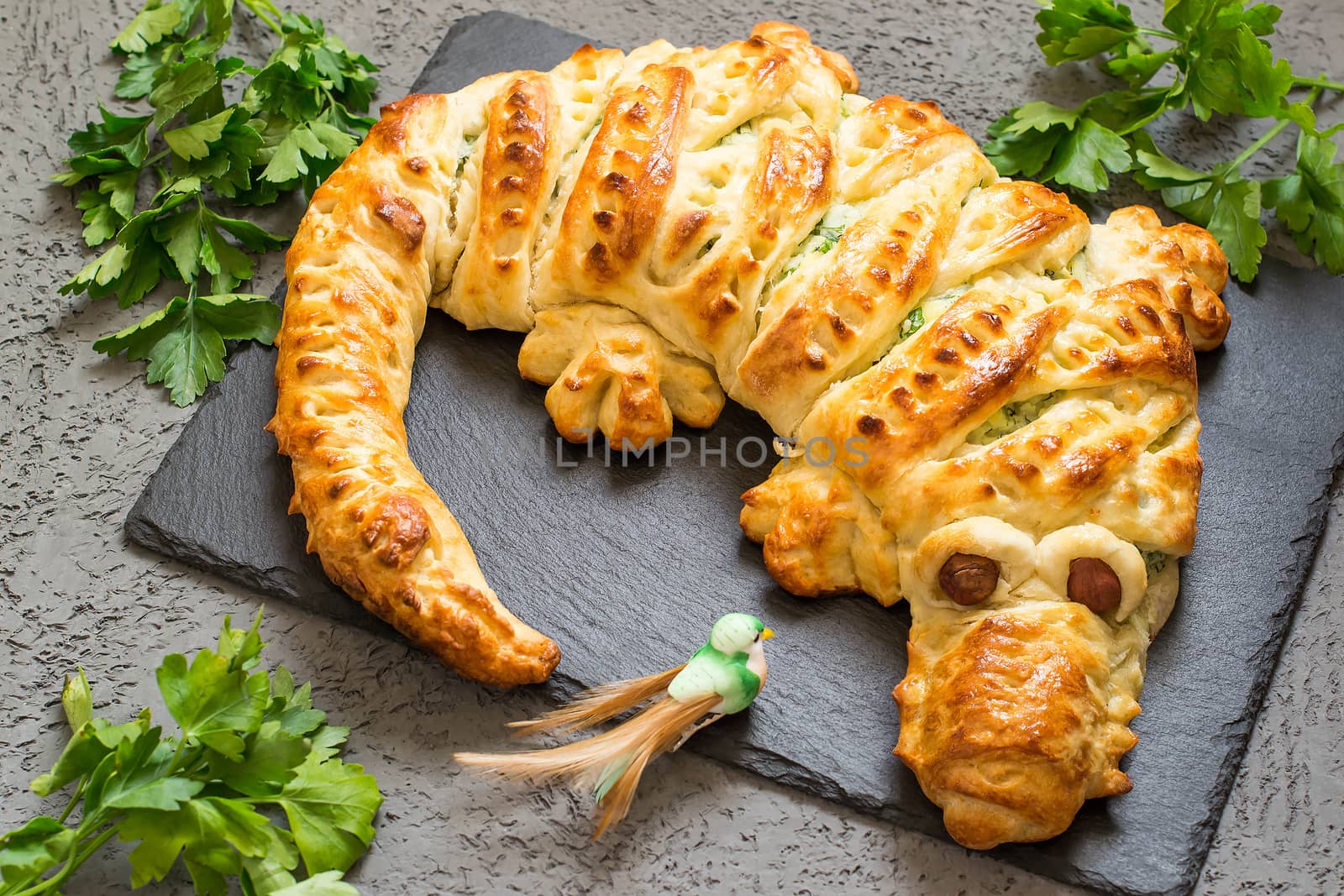 Original cake in form of crocodile with potatoes, cheese and herbs and knives. Cake is served to Halloween party as fun and spooky monster