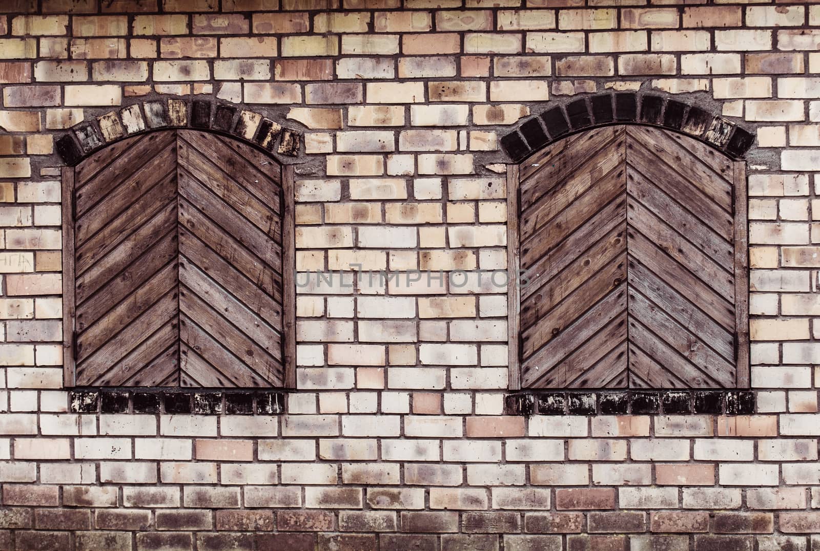 Two windows with closed wooden shutters on a brick by infinityyy
