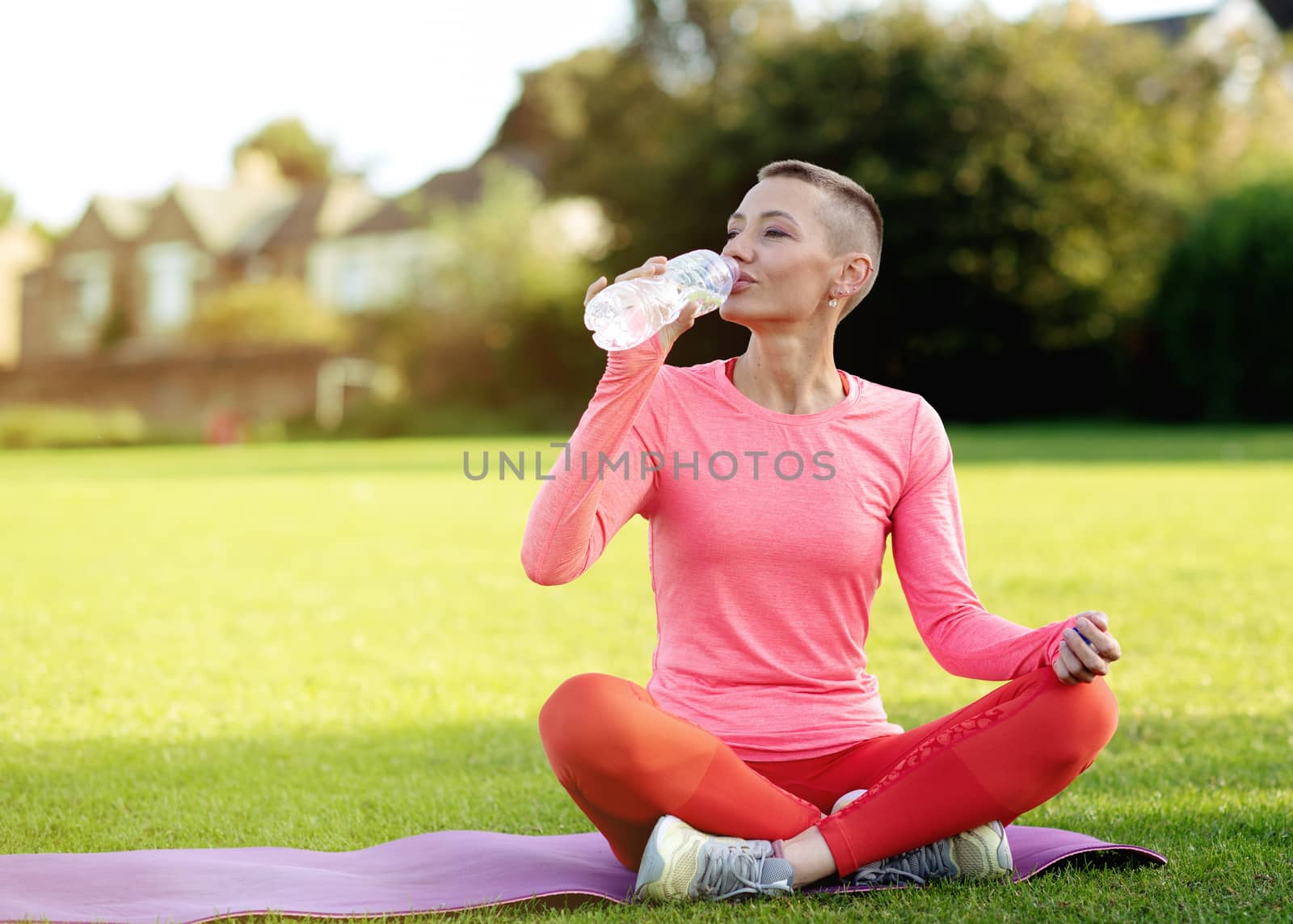 woman drinking water after exercising on the grass by Iryna_Melnyk