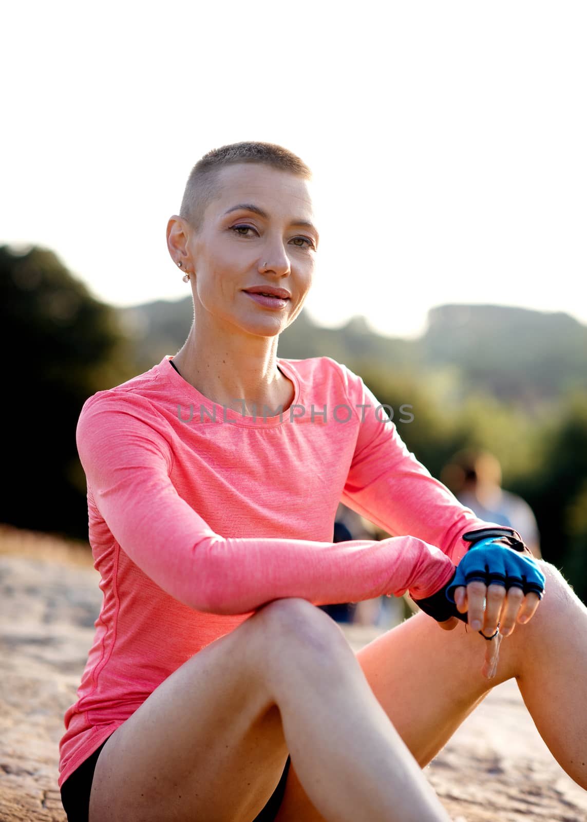 portrait of a woman sitting on the top of cliff in the park after exercise