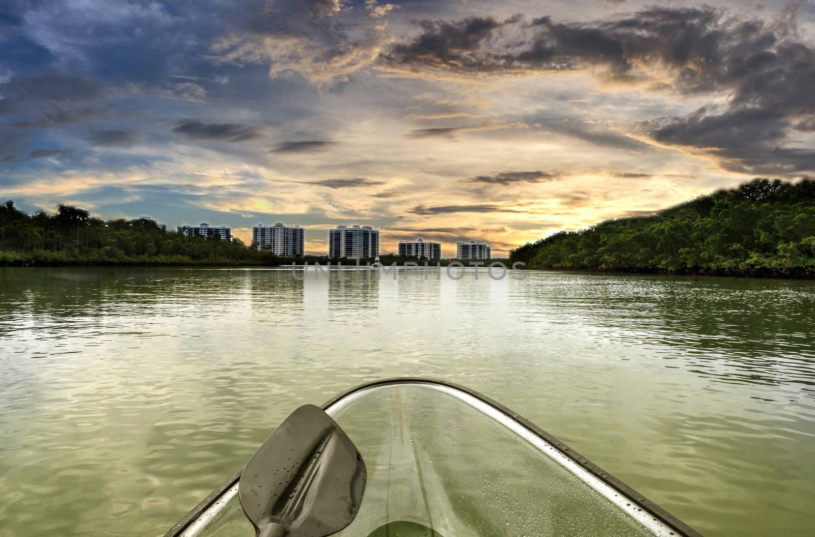 Sunset over clear see-through kayak forges its way through the waters of Delnor-Wiggins pass in Bonita Springs, Florida.