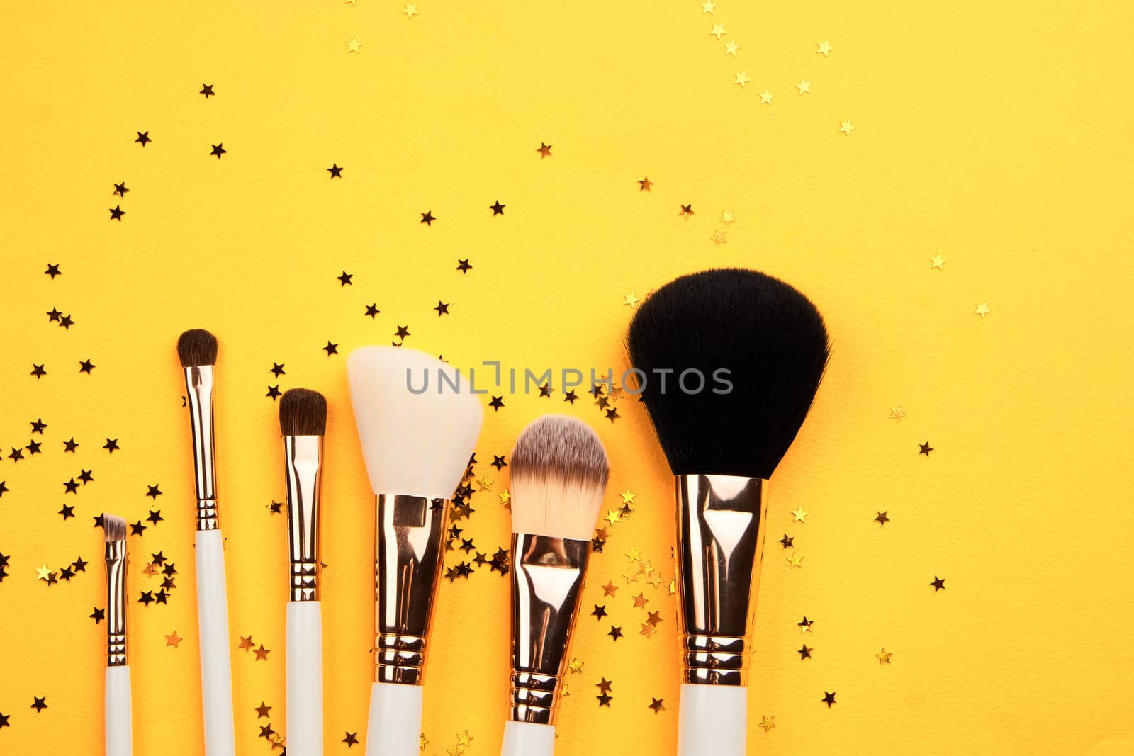 makeup brushes of different sizes on yellow background cropped view Copy Space. High quality photo