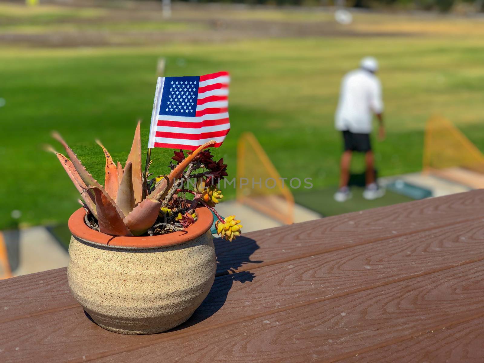 Patriotic flower pot with American flags and golfer on the background. by Bonandbon