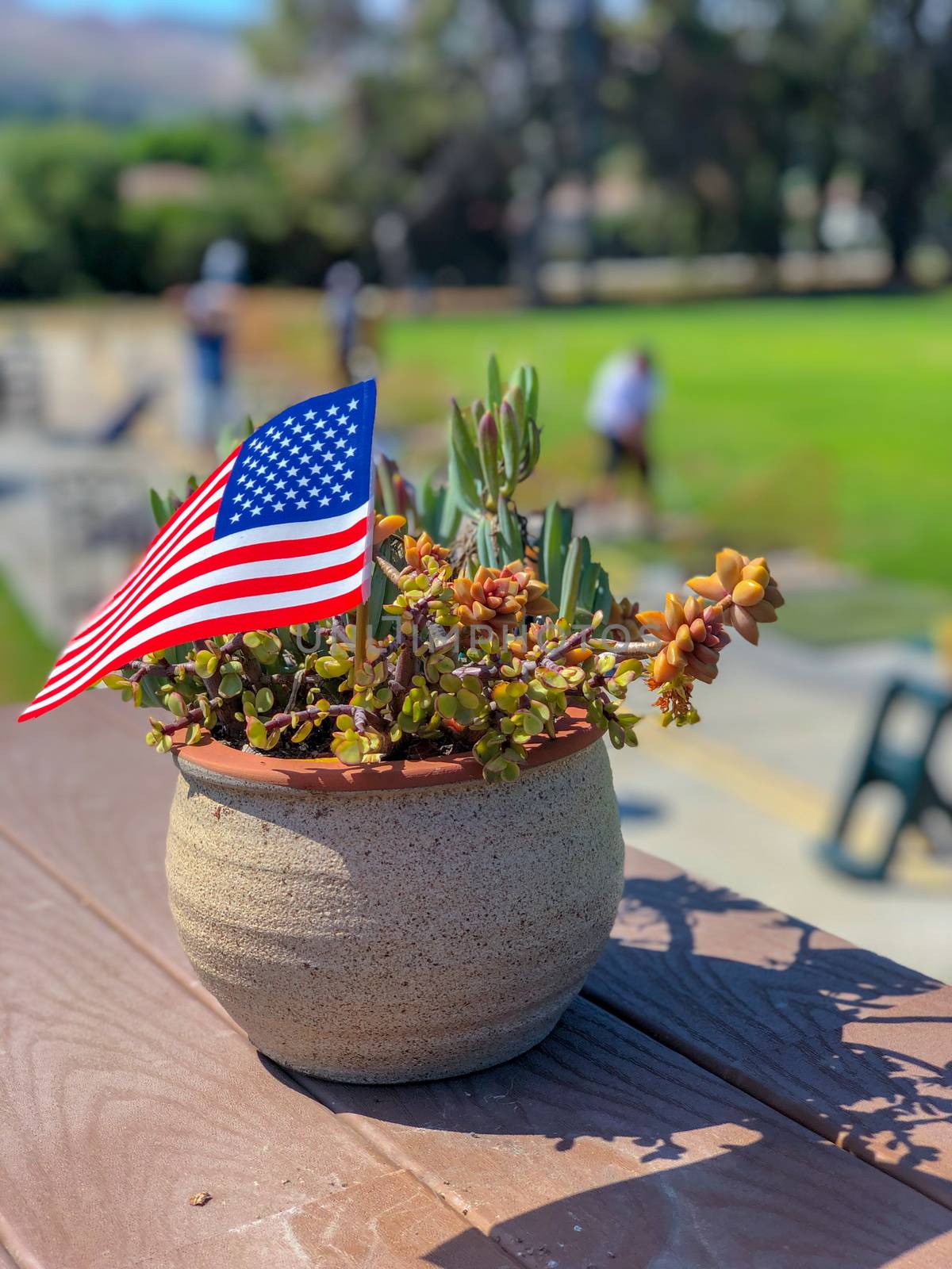 Patriotic flower pot with American flags and golfer on the background. American flag decoration.