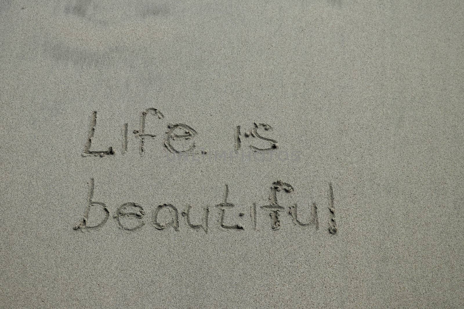 Life is beautiful, positive thinking concept. Inspirational quote written on sand by Sanatana2008