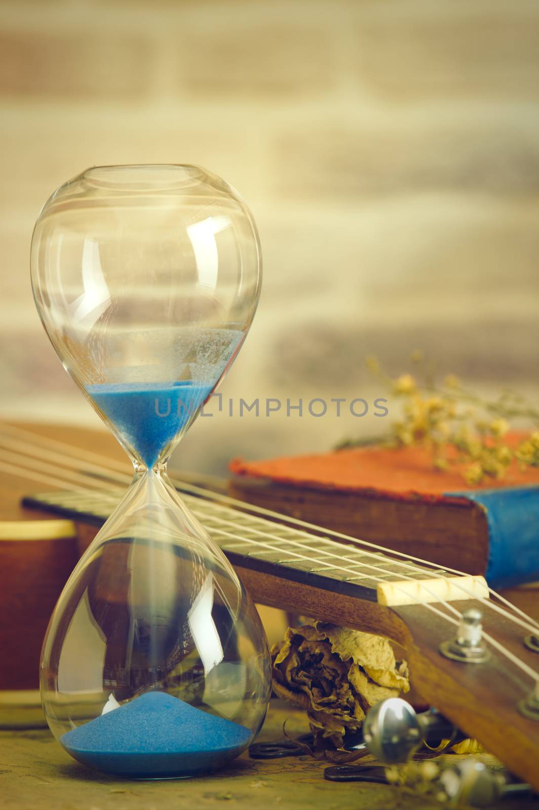 Vintage hourglass and ukulele with an old book and brass pen. by SaitanSainam