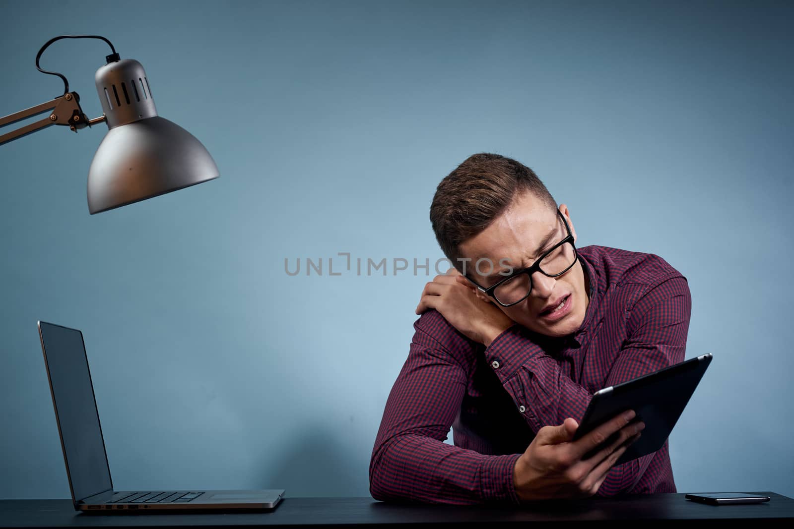 Male manager in the office with a tablet in his hand and a laptop on the table. High quality photo