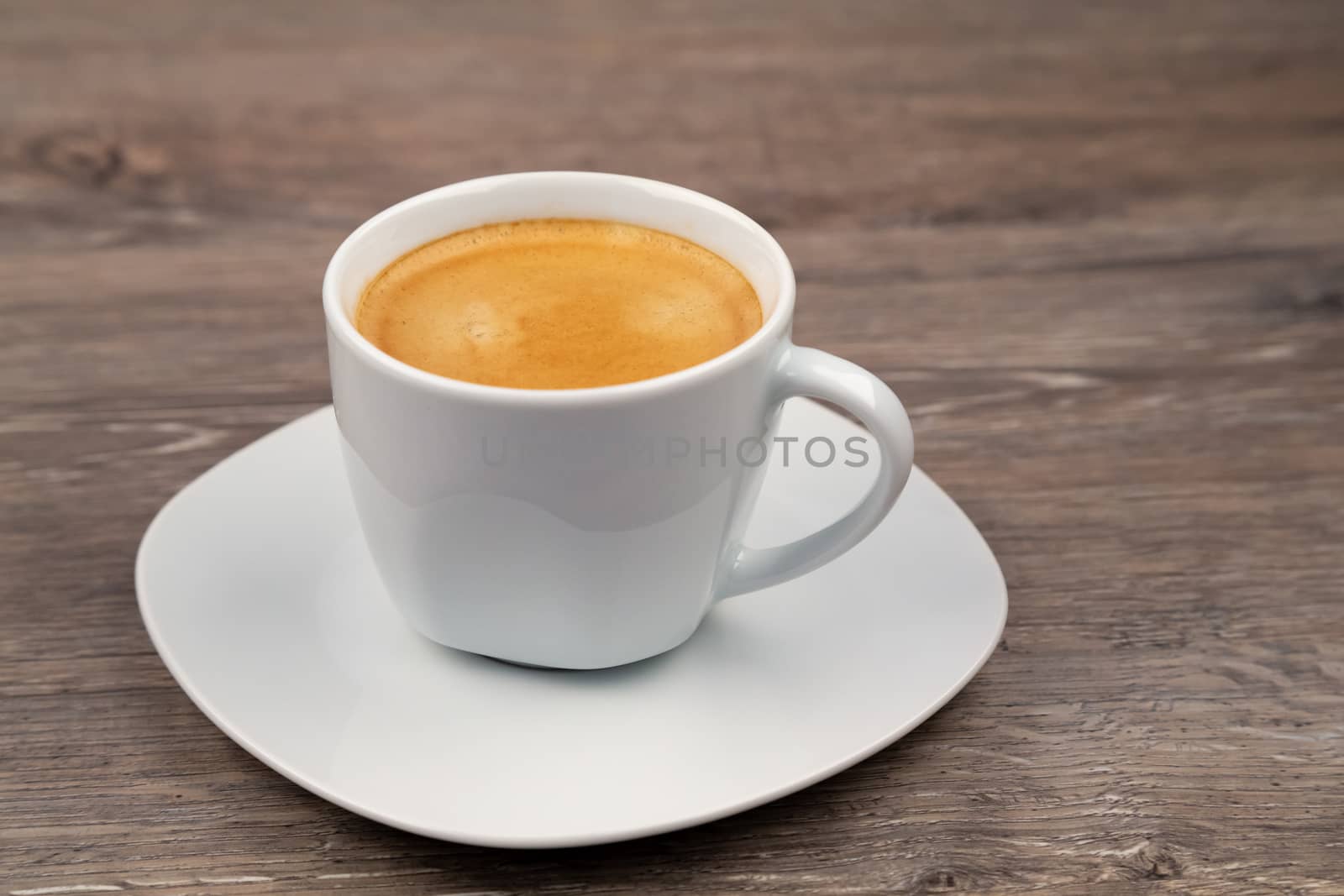 One white cup with coffee on a wooden background