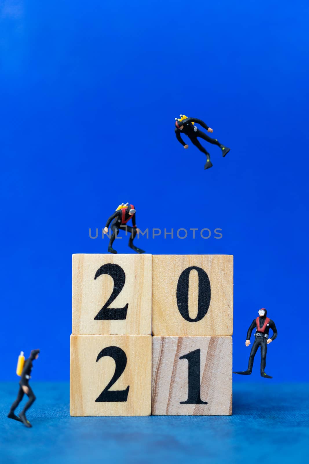 Miniature people divers diving around wooden block 2021 , Happy new Year concept