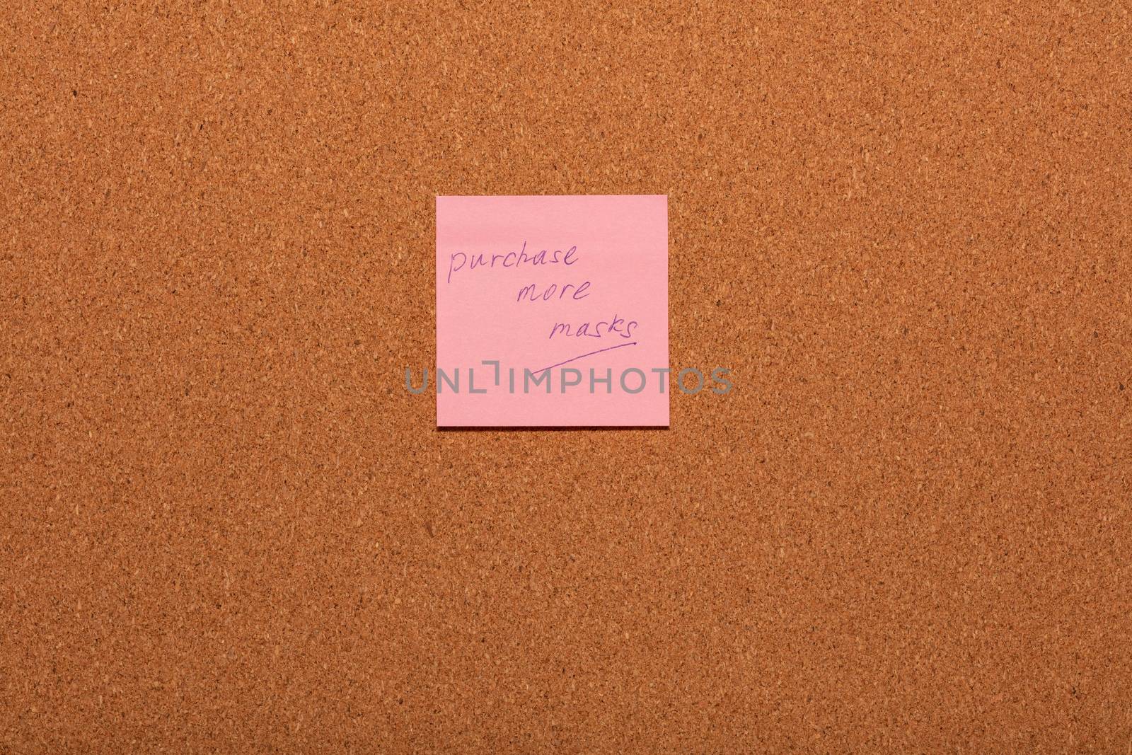 Reminder Purchase more masks handwritten on a pink sticker on a cork notice-board. by DamantisZ