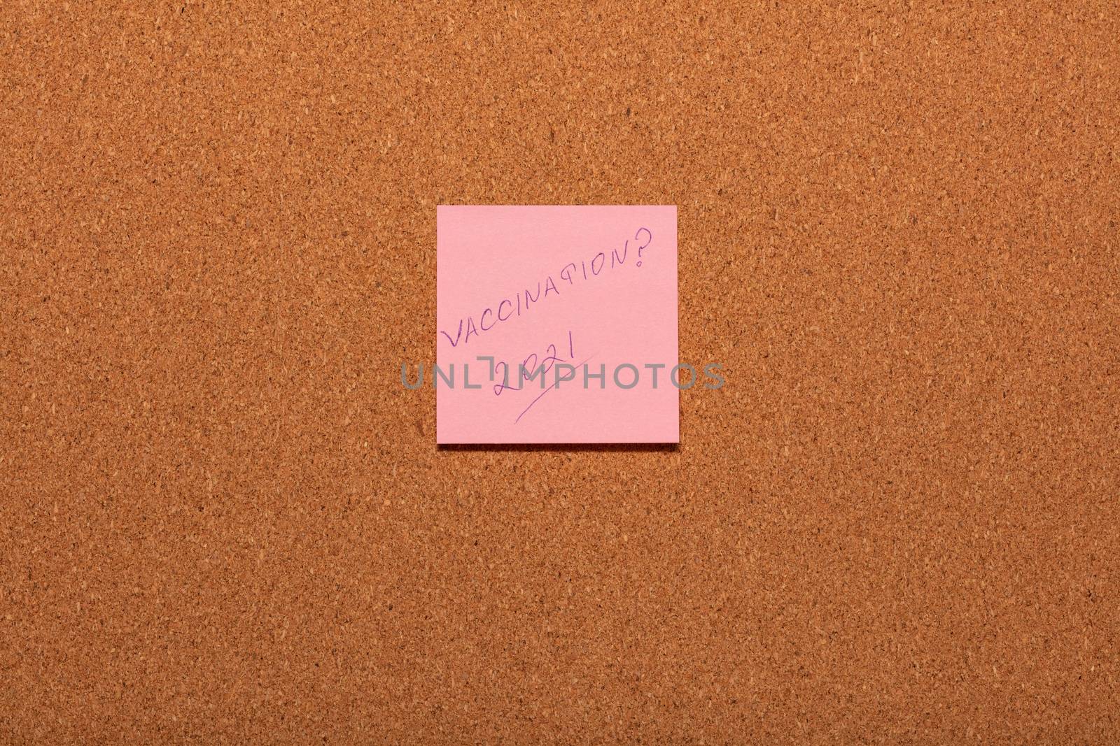 Vaccination 2021? handwritten on a pink sticker on a cork notice-board. by DamantisZ