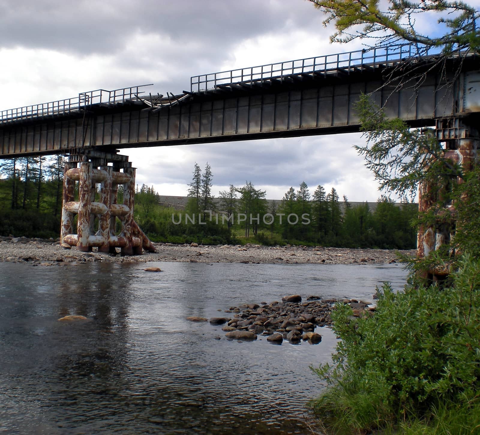 Damaged iron bridge over the river. The old bridge.