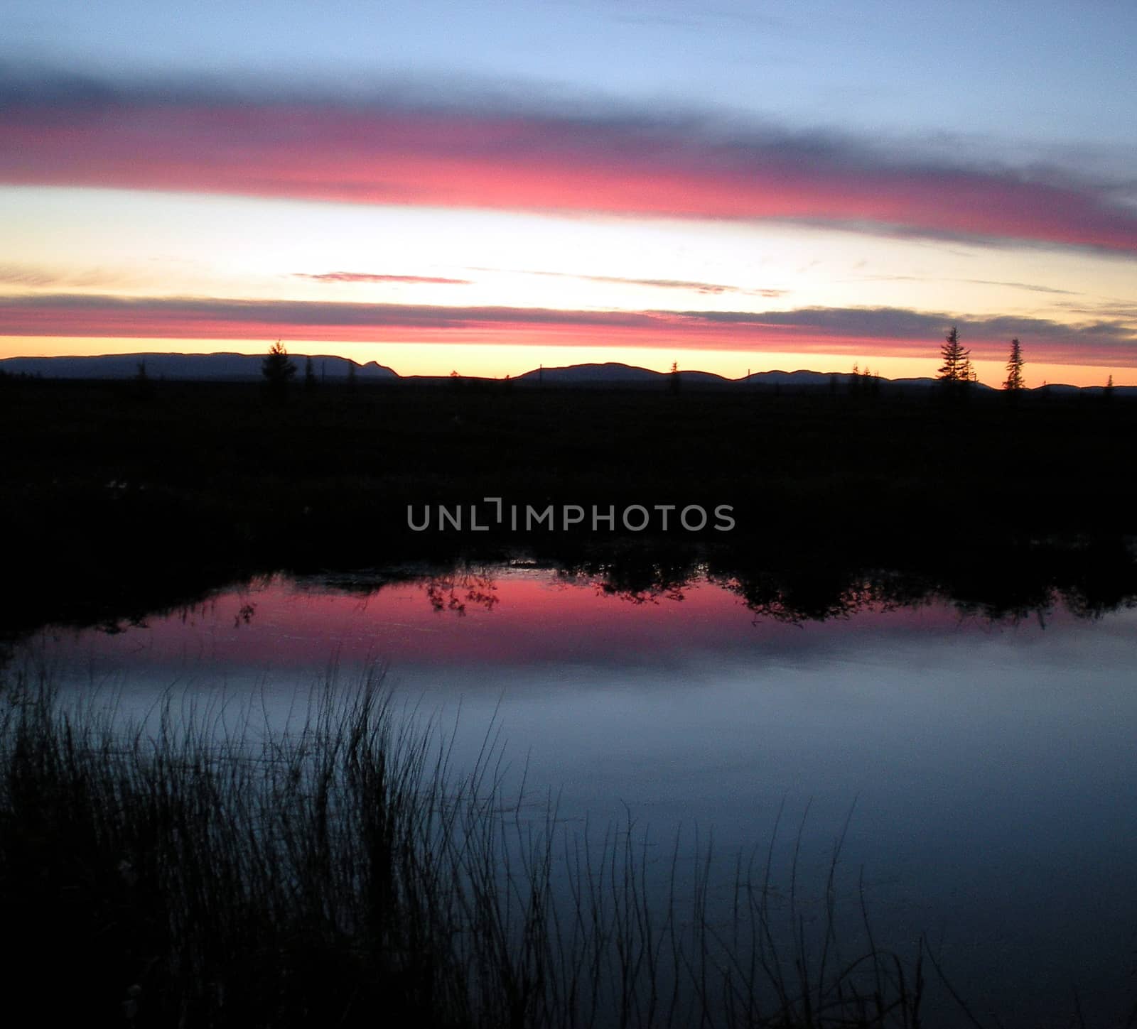 Sunset over the lake. Red sky and black horizon.