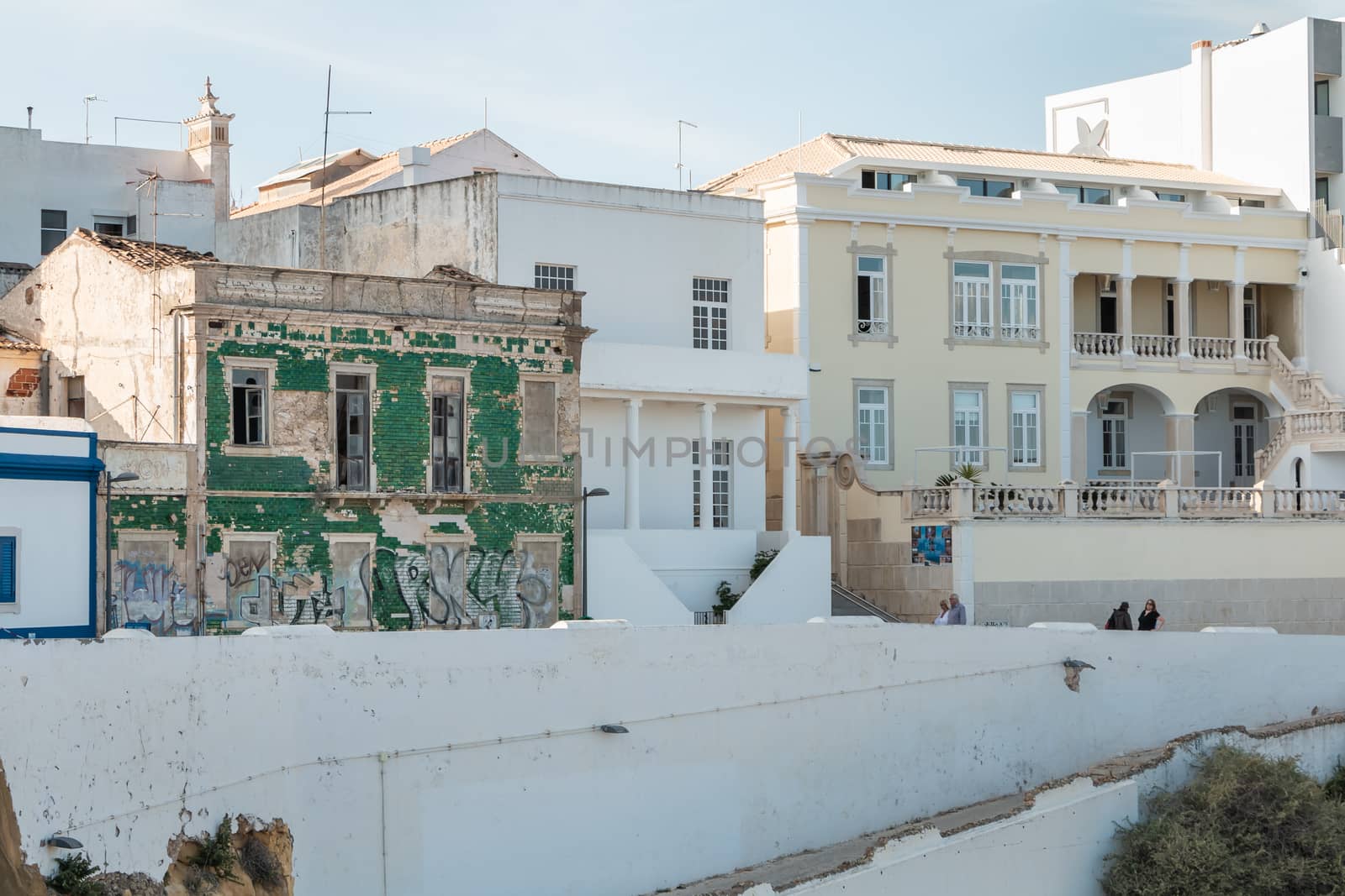 Albufeira, Portugal - May 3, 2018: People looking at a ruined building on the seafront in an upscale part of the resort town on a spring day