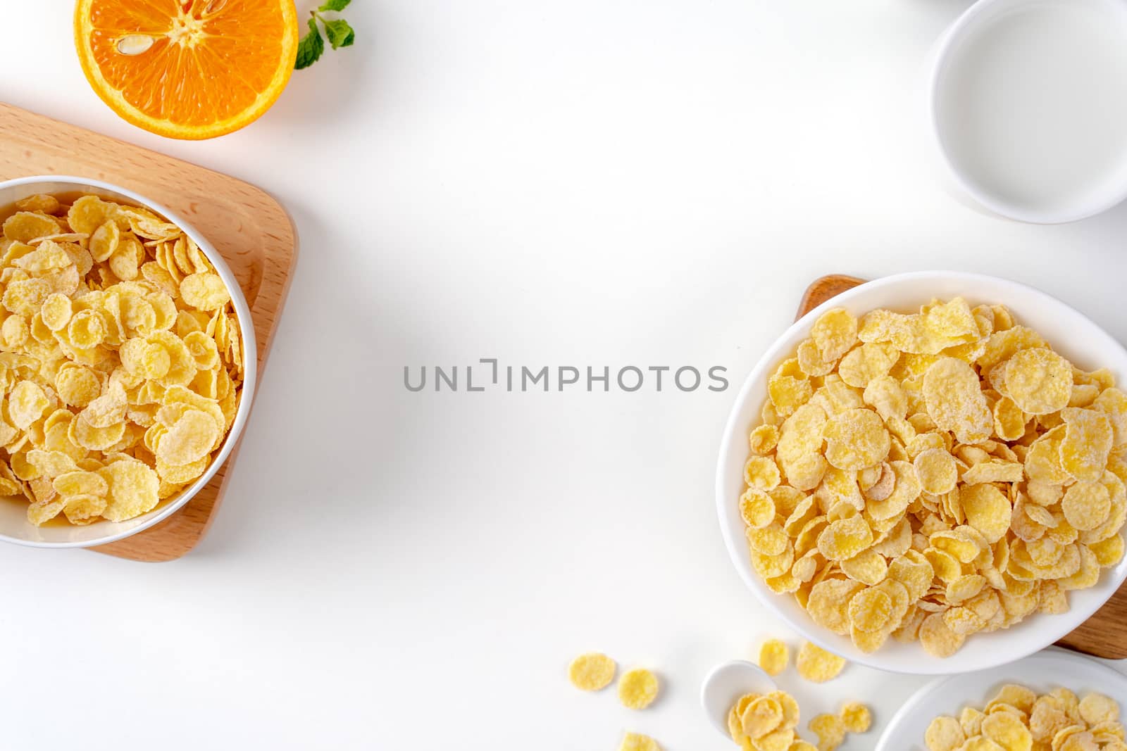 Top view of corn flakes bowl sweeties with milk and orange on white background, flat lay overhead layout, fresh and healthy breakfast design concept.