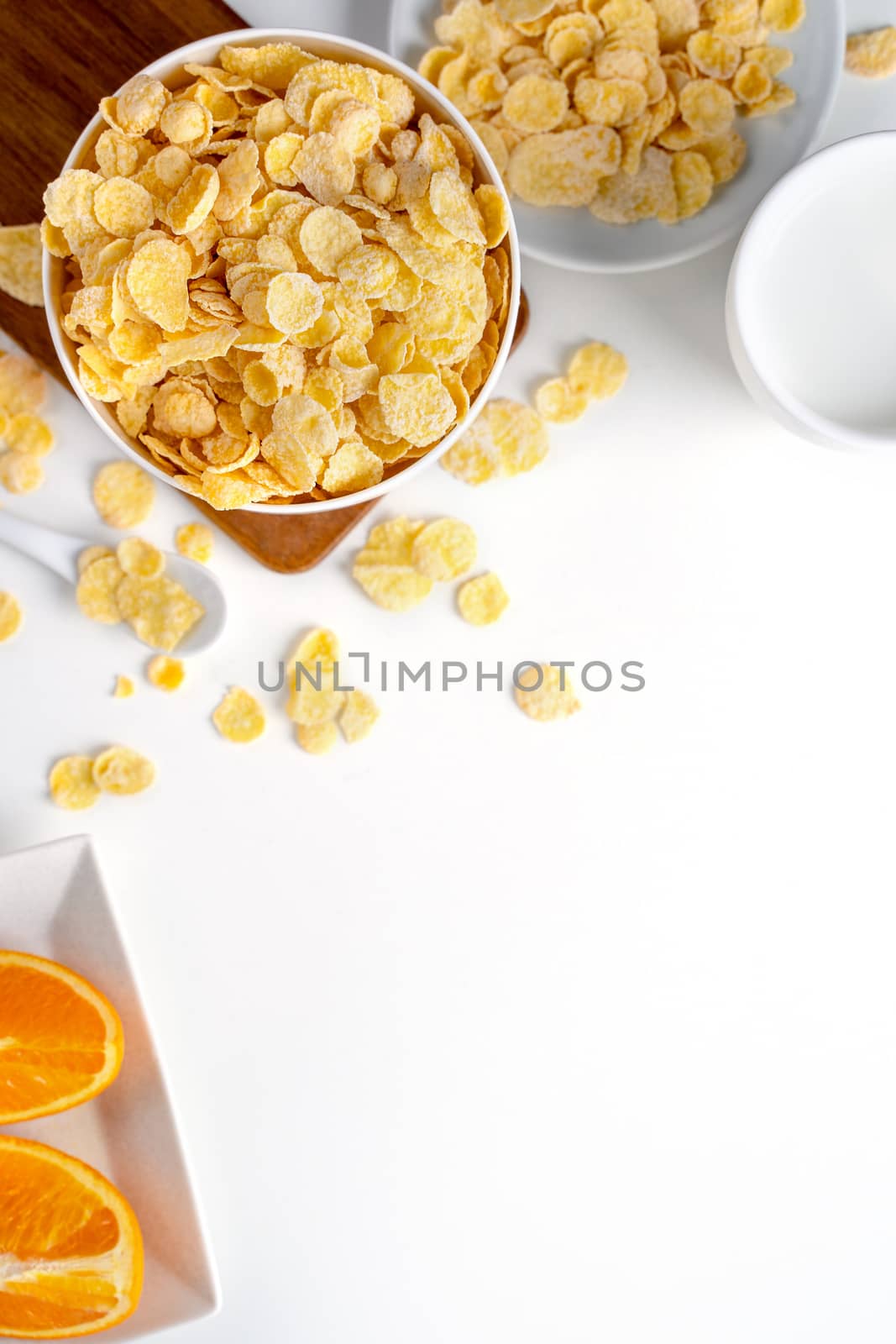 Top view of corn flakes bowl sweeties with milk and orange on white background, flat lay overhead layout, fresh and healthy breakfast design concept.