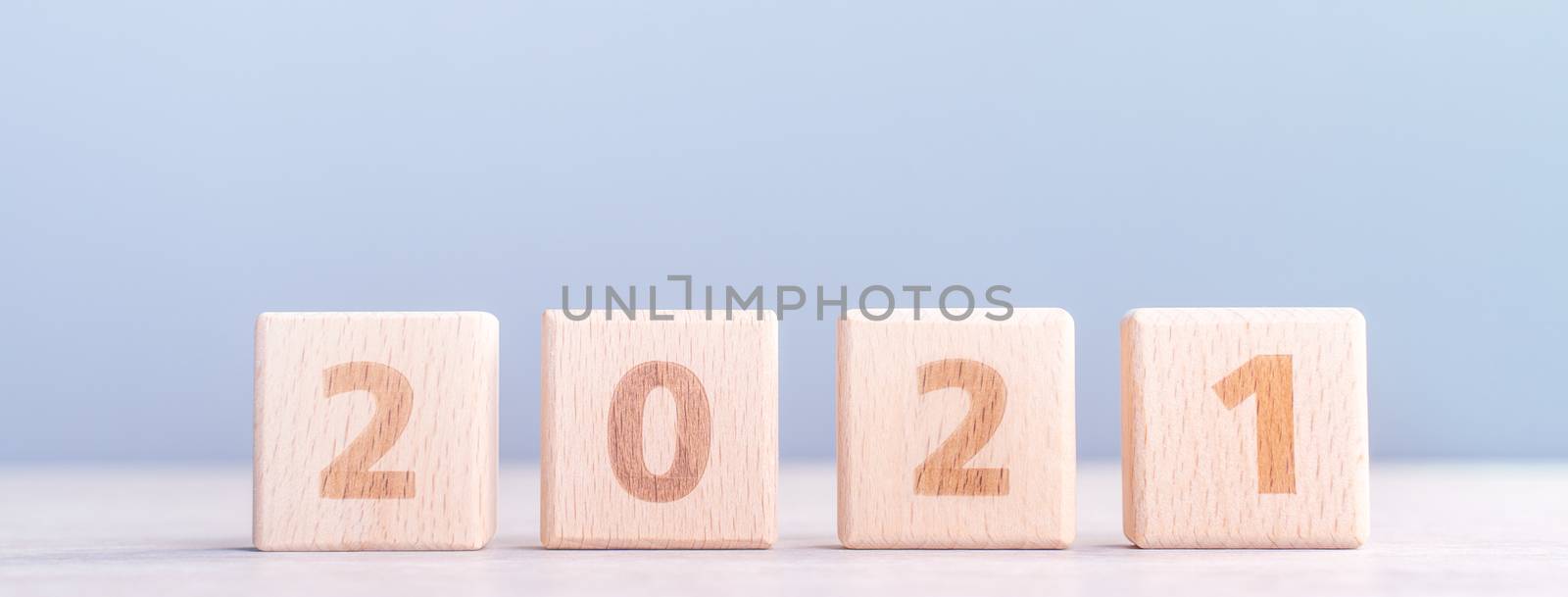 2021 New Year abstract design concept - Number wood block cubes isolated on wooden table and light mist blue background.