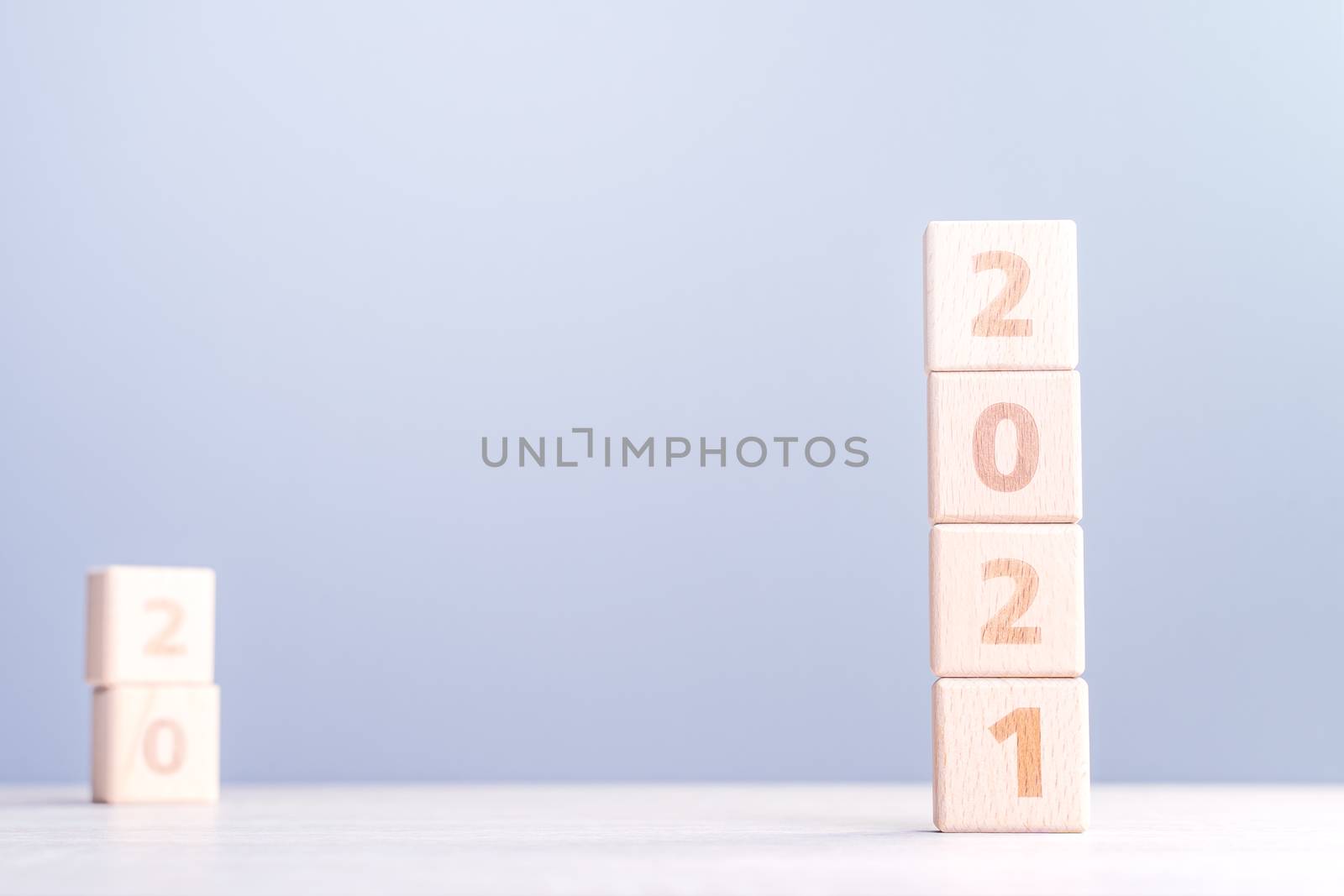 2021 New Year abstract design concept - Number wood block cubes isolated on wooden table and light mist blue background.