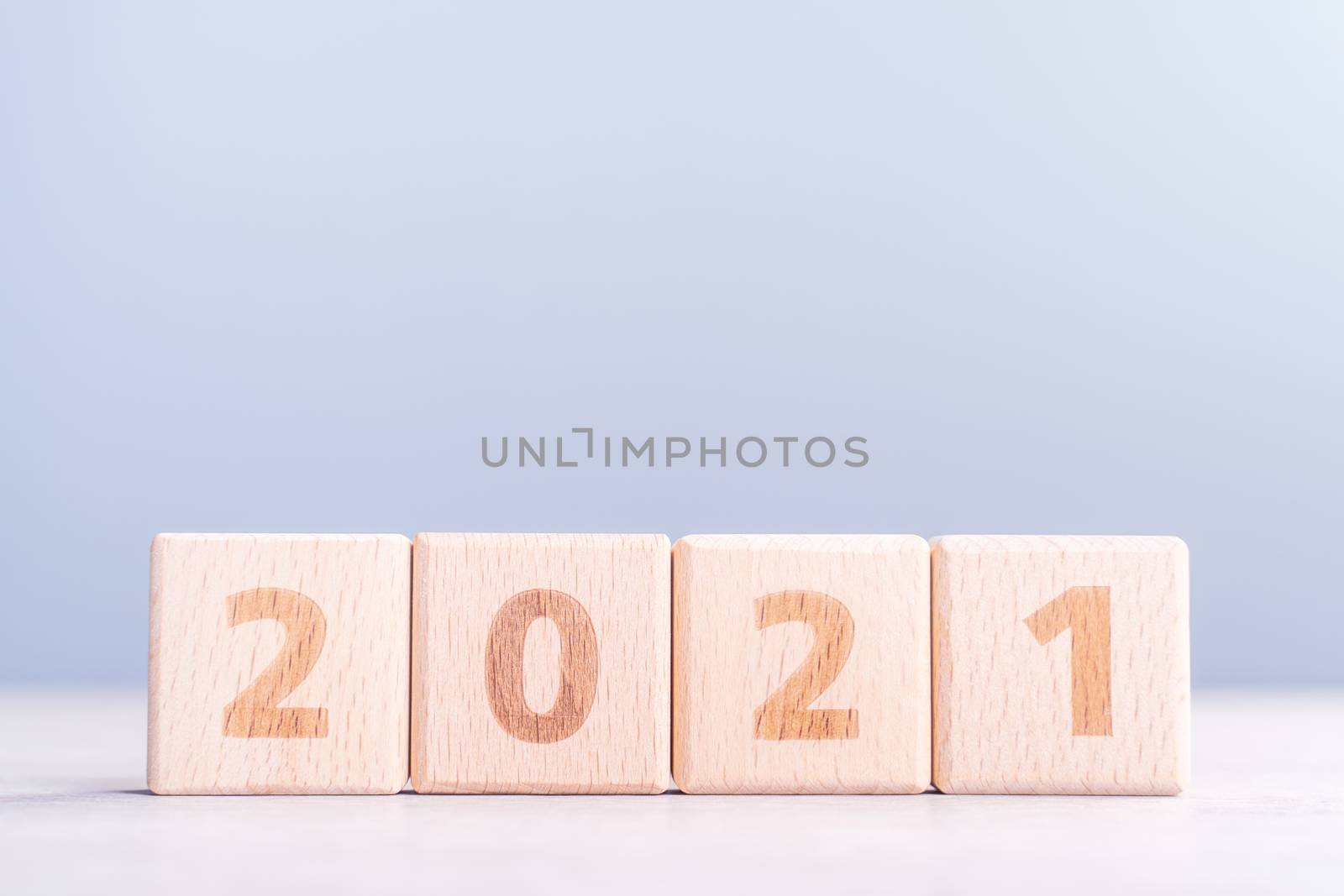 2021 New Year abstract design concept - Number wood block cubes isolated on wooden table and light mist blue background.