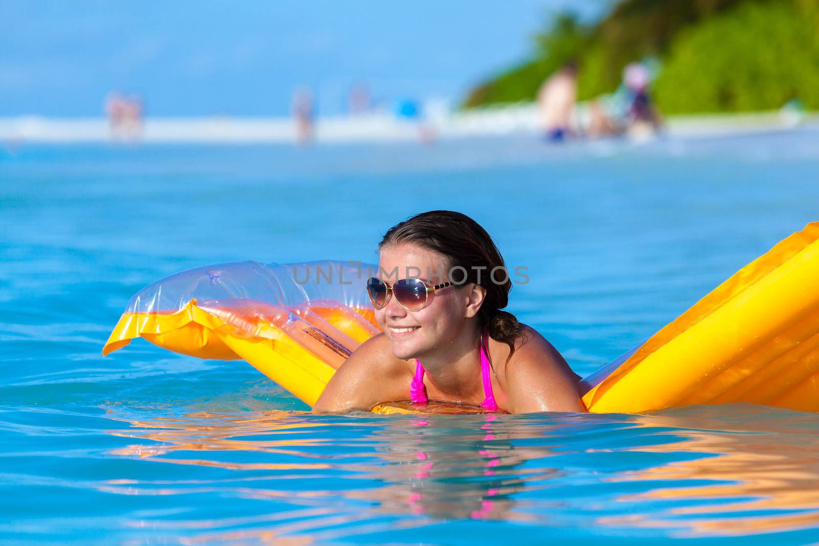 Maldives, a young woman in the water on an air mattress