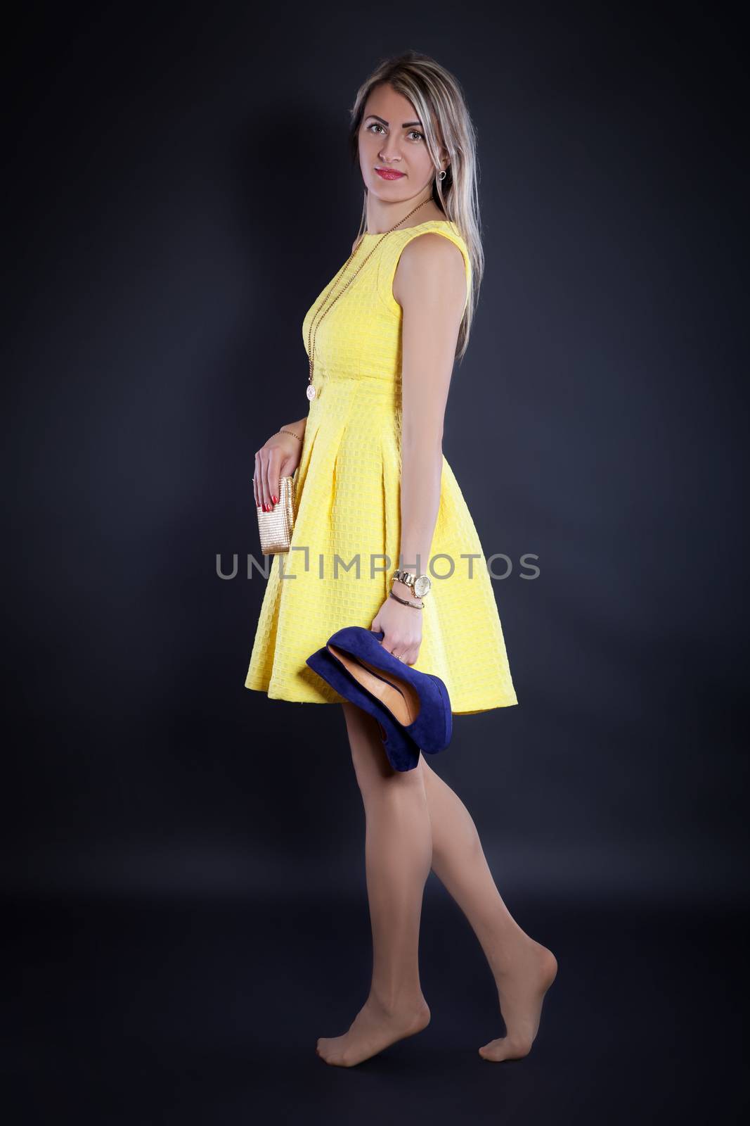 Young woman in a yellow dress with high heels in the hand