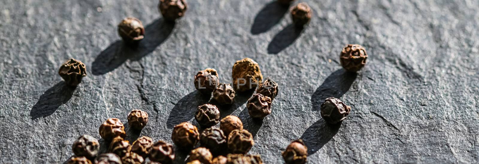 Black pepper closeup on luxury stone background as flat lay, dry food spices and recipe ingredients