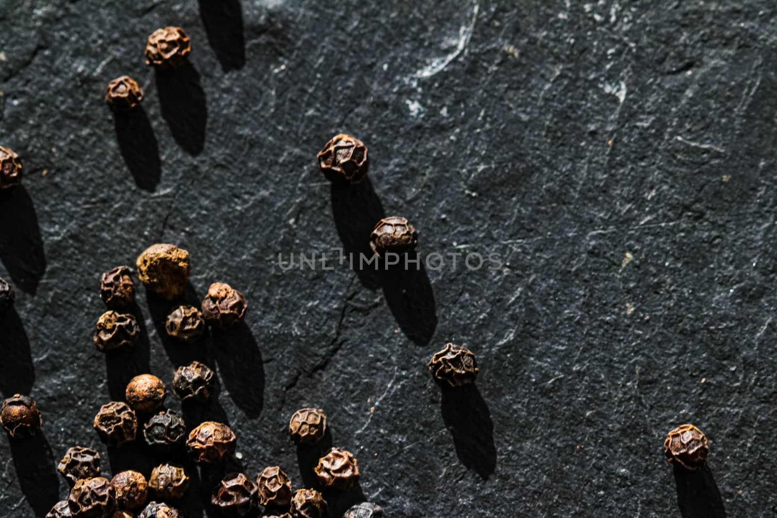 Black pepper closeup on luxury stone background as flat lay, dry food spices and recipe ingredients