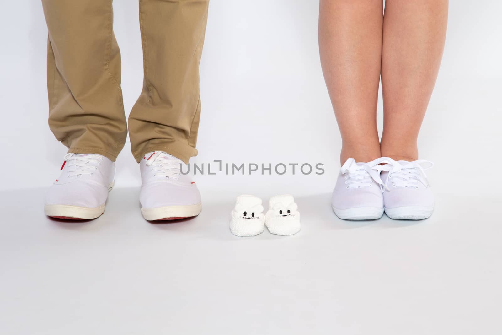 Two pairs of feet from the parents and shoes from an unborn baby, studio