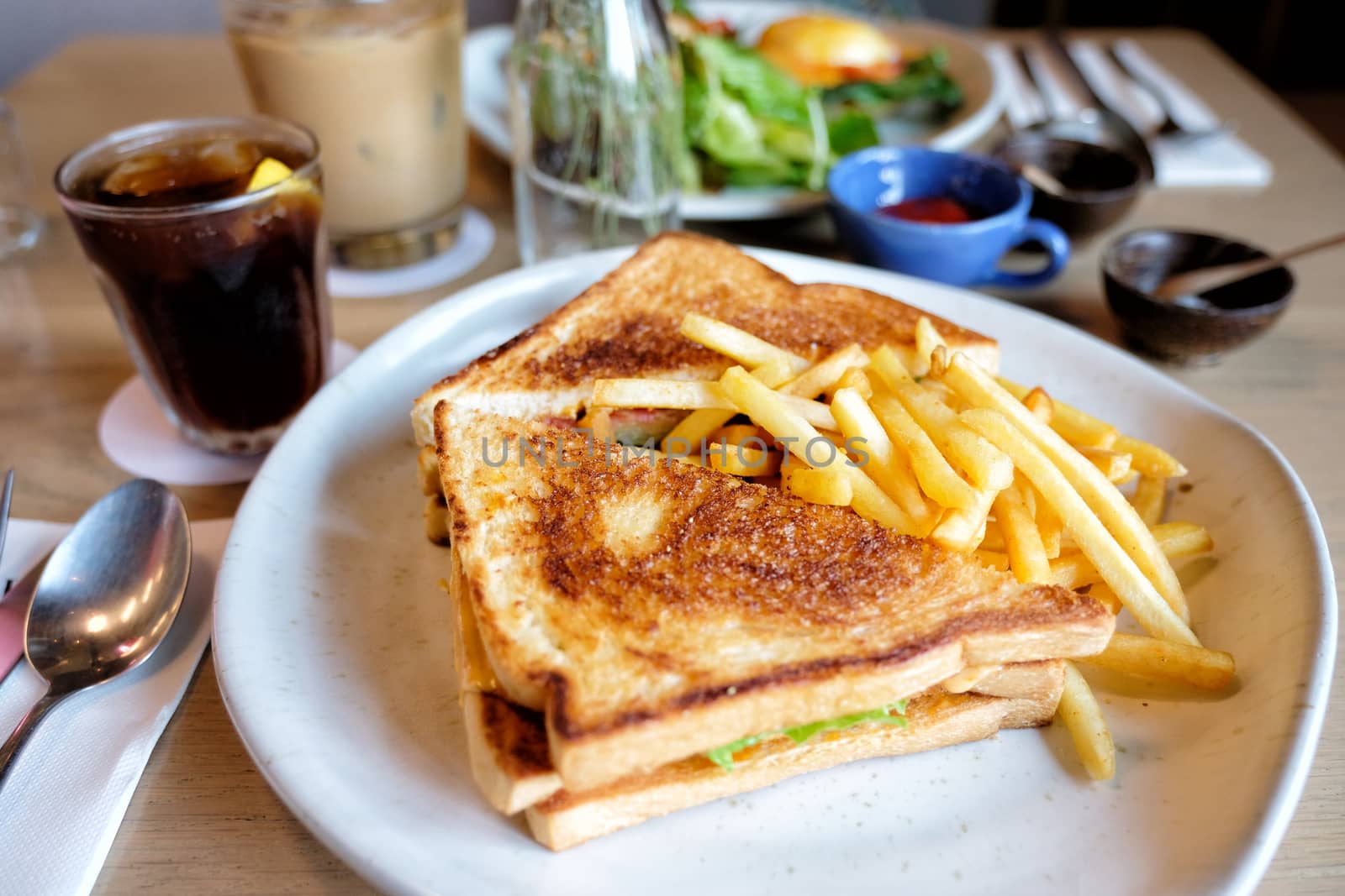 Club sandwich with chicken breast, bacon, tomato, cucumber, herbs and french fries