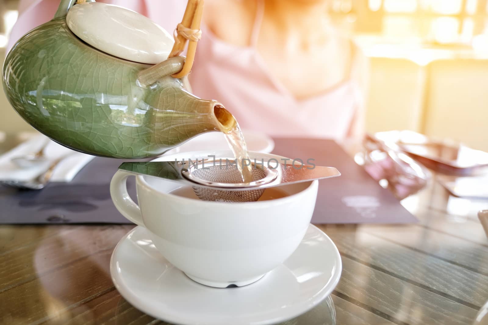 Hand that pours chinese tea from glass kettle to smal cup in mor by Surasak