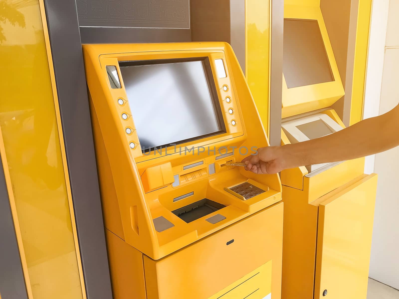 Man's hand is inserting an ATM card in a bank cash machine.