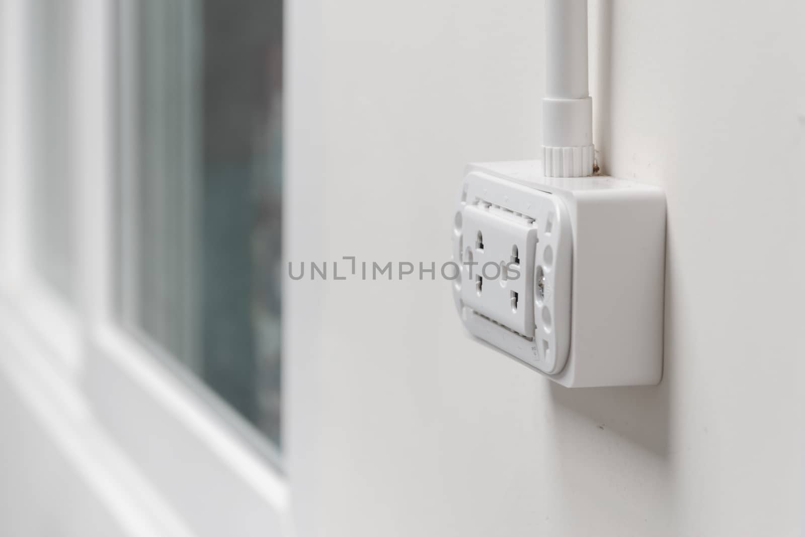 Close up of white plug on white room wall.