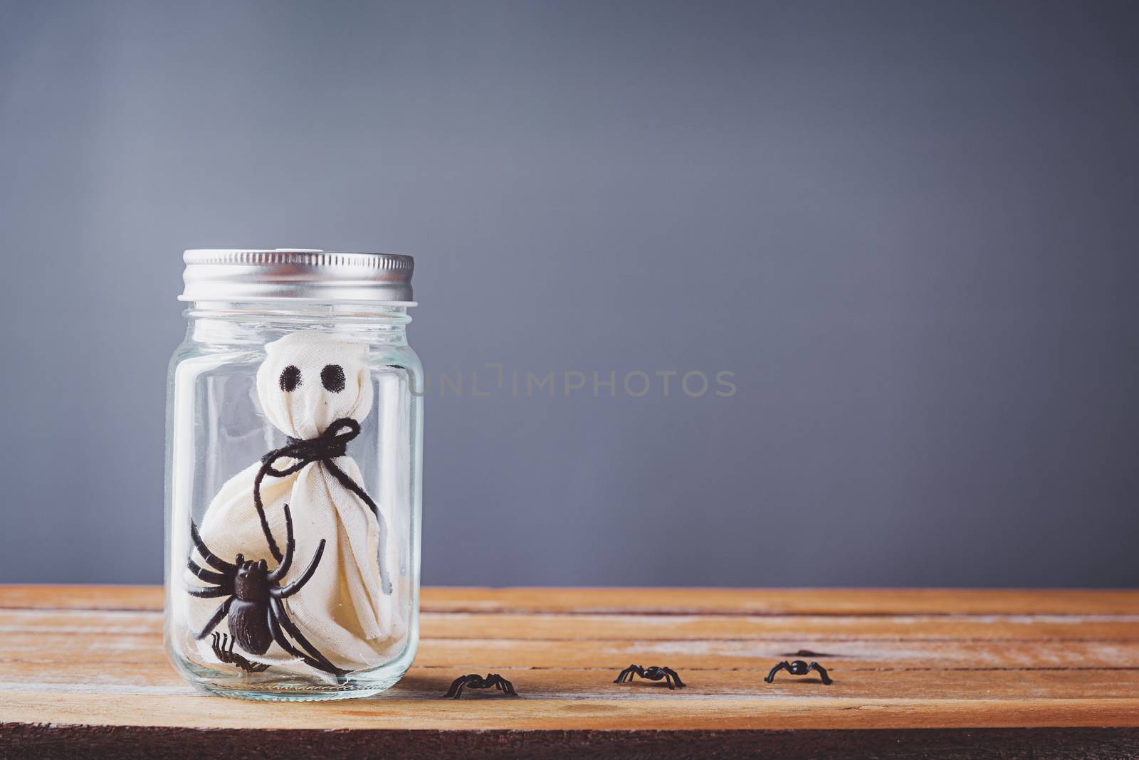 closeup white ghost and spider in jar on wooden by Sorapop