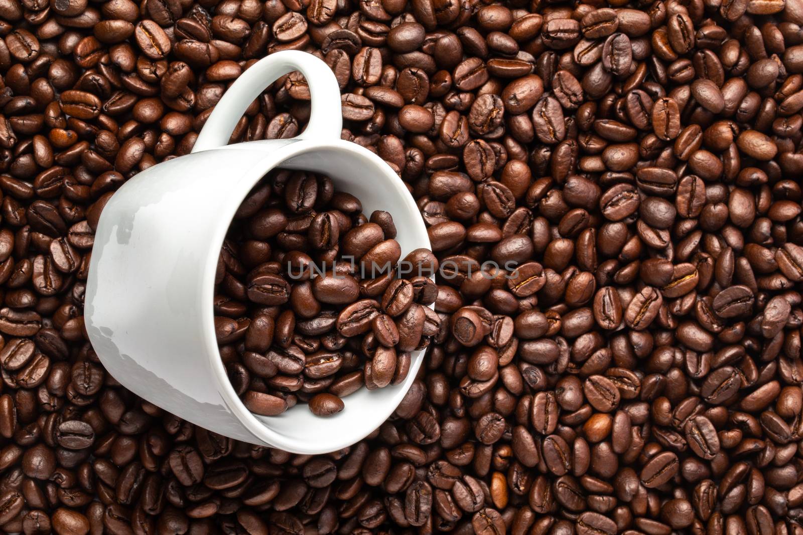 A White cup with coffee beans on a background of coffee beans