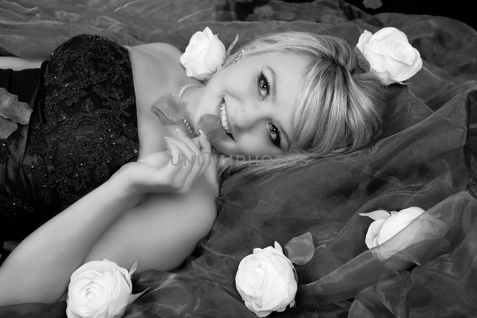 Young blonde woman is lying in roses