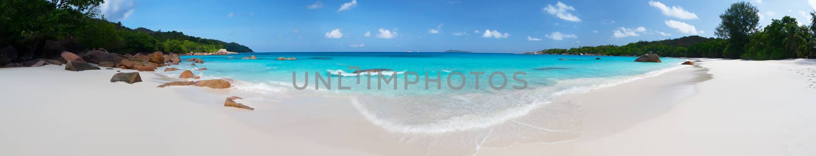 Panorama of the beach with big stones and white sand and a blue sky