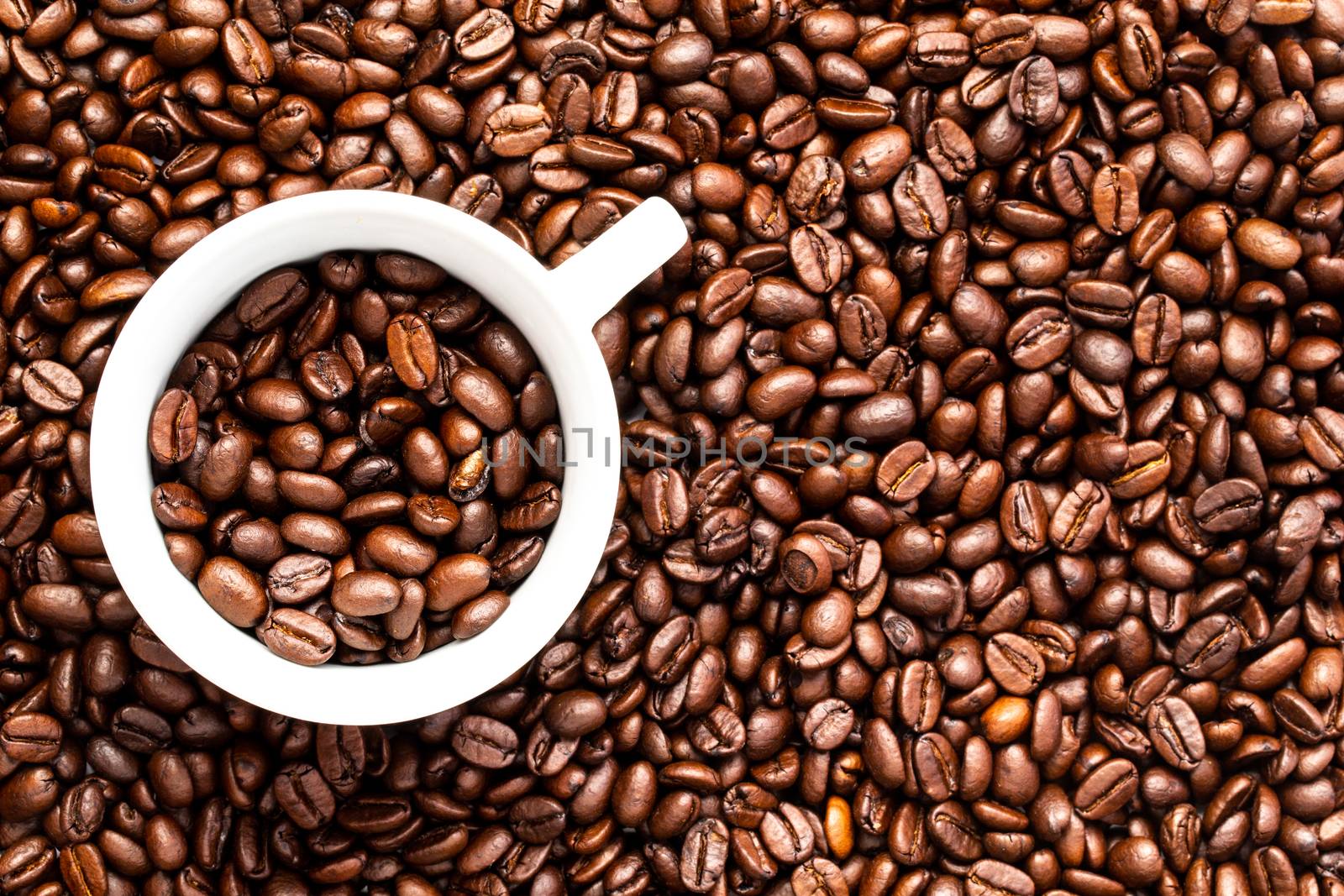 A White cup with coffee beans on a background of coffee beans
