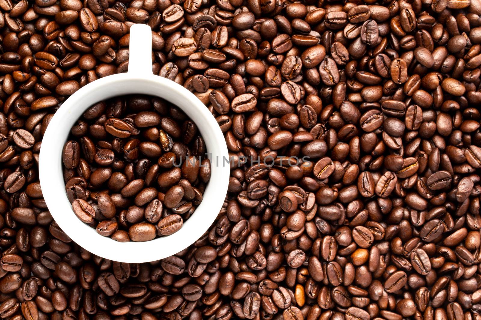 A White cup with coffee beans on a background of coffee beans