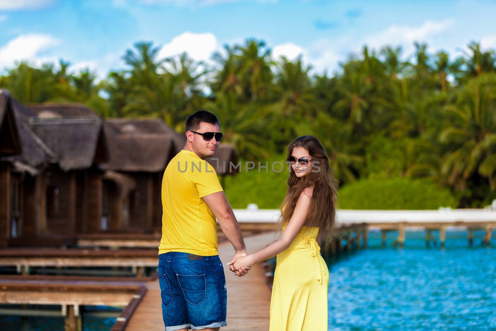 Maldives, a couple walking along the bridge by the villas