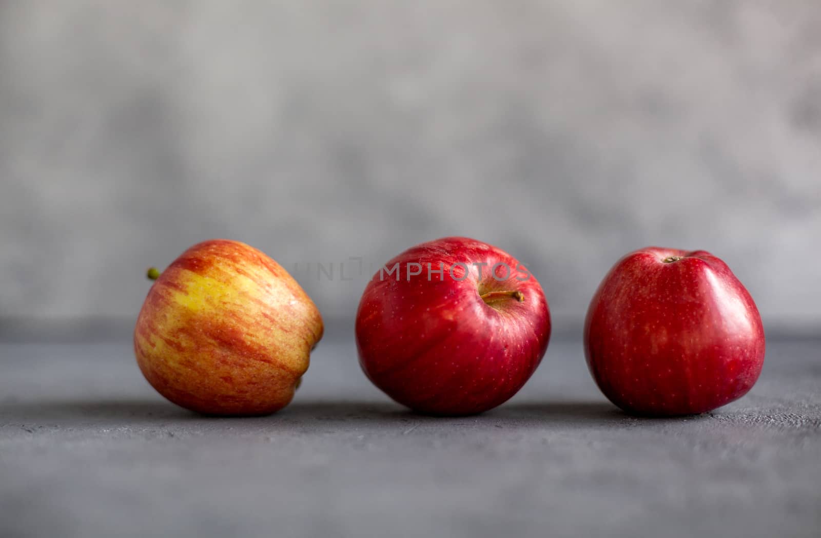 Three Ripe garden red apples on gray concrete. Fruits concept of the fall harvest. Space for text.