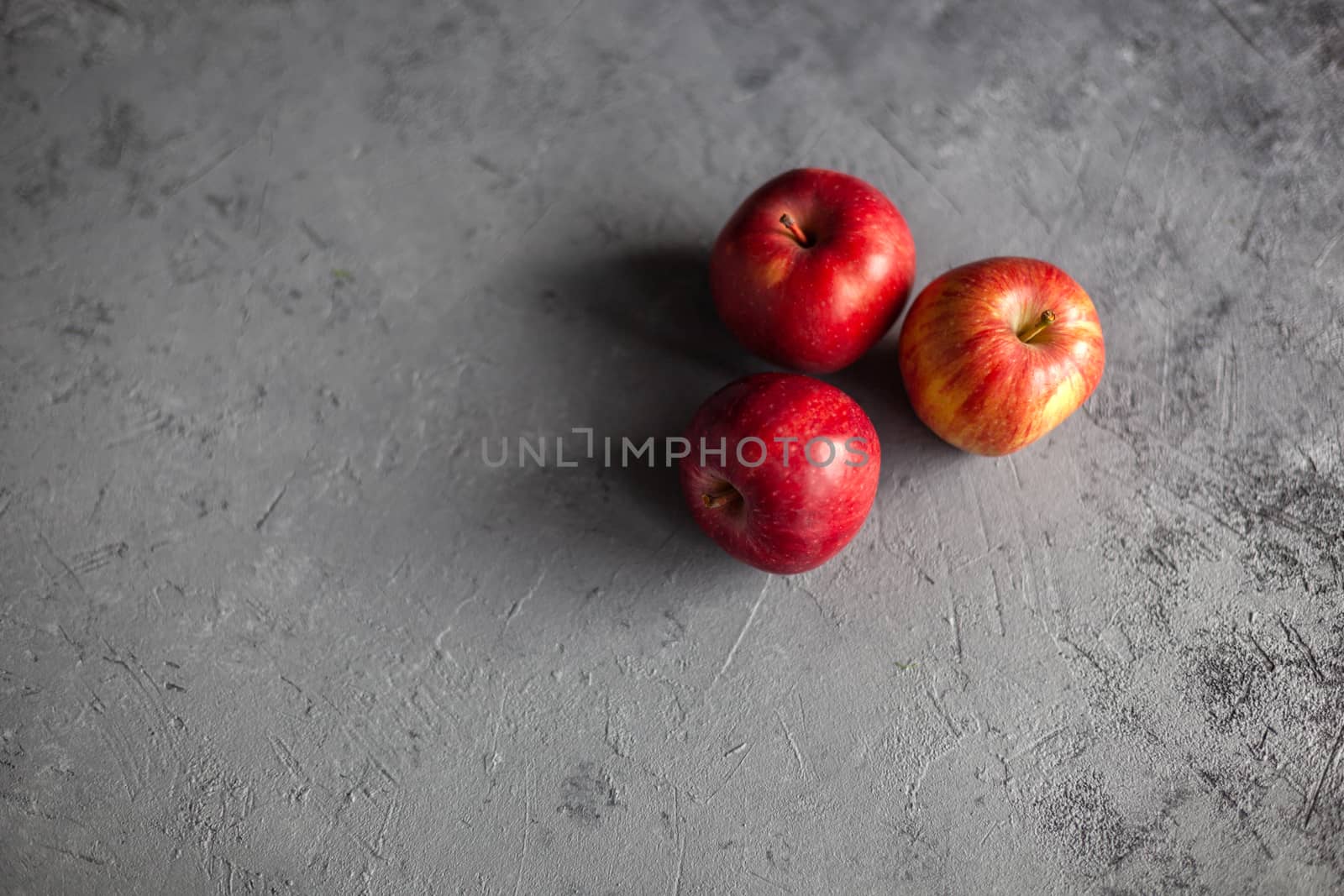 Three Ripe garden red apples on gray concrete. Fruits concept of the fall harvest. Space for text.