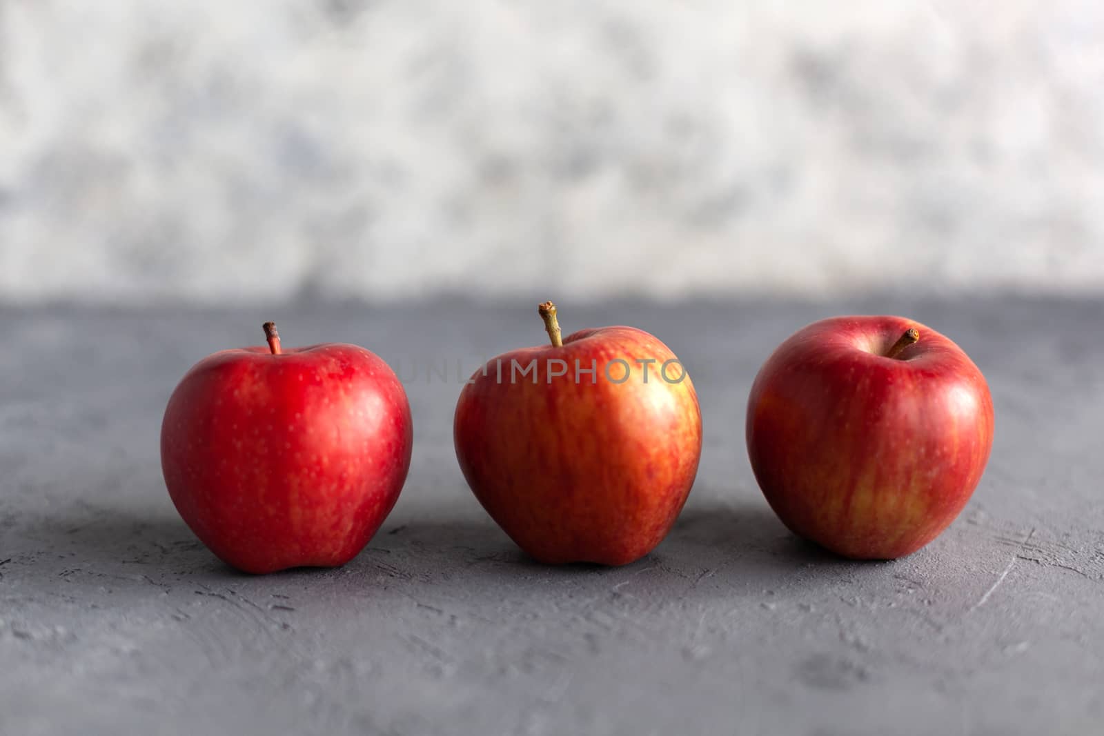 Three Ripe garden red apples on gray concrete. Fruits concept of the fall harvest. Space for text.