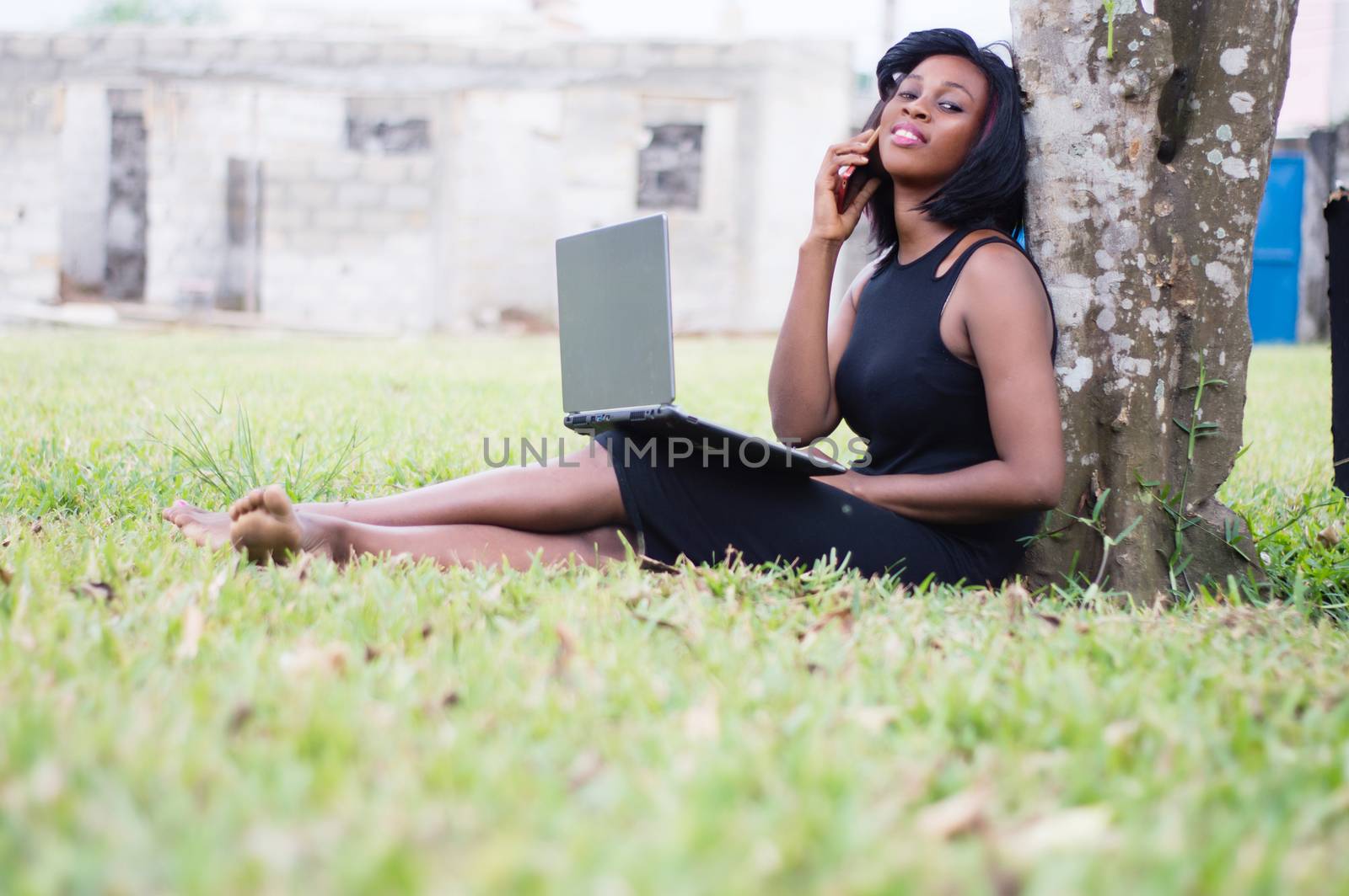 young woman in communication in a park sitting with a laptop on her legs