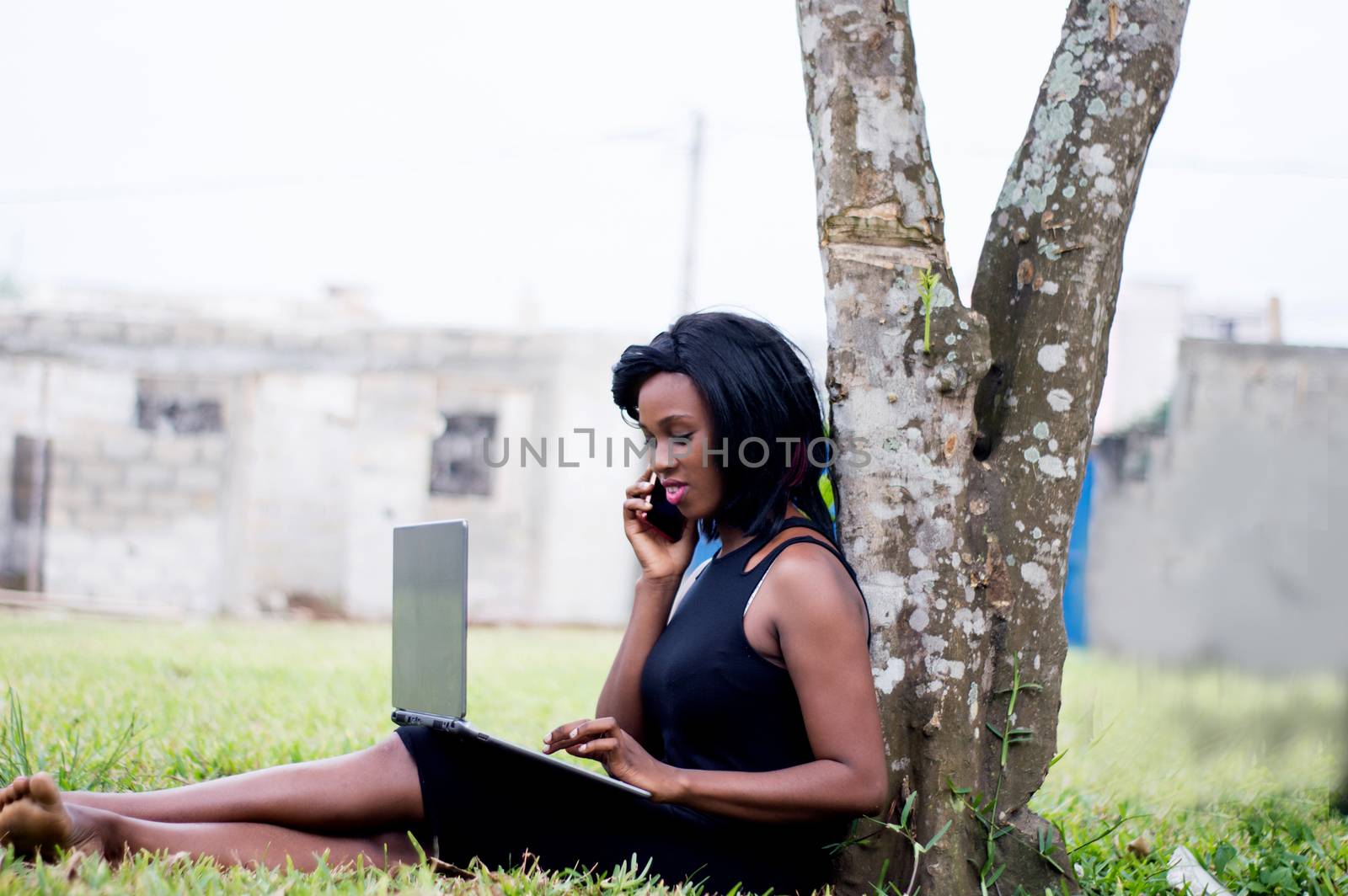 young woman in communication in a park sitting with a laptop on her legs