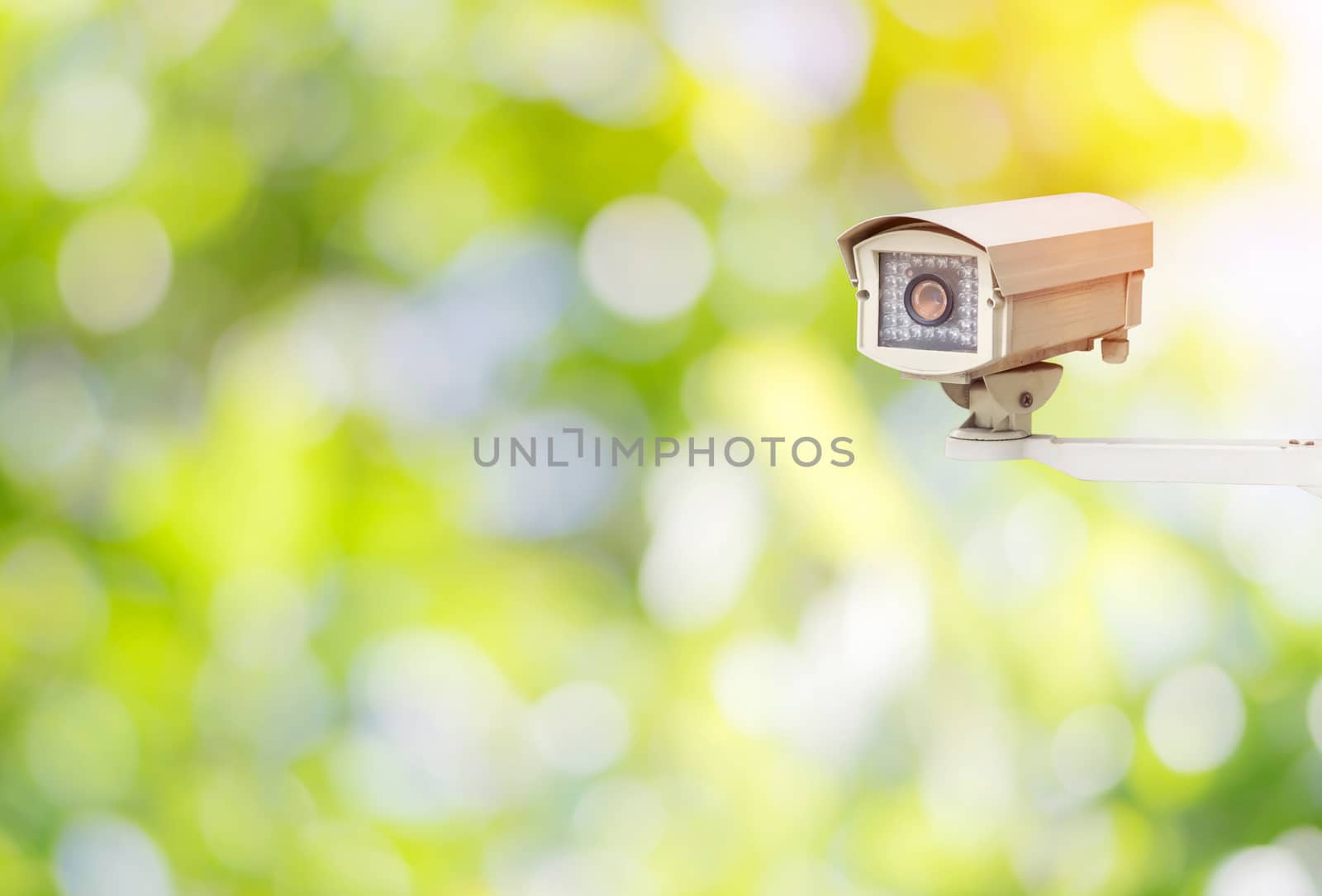 Closeup CCTV or surveillance camera in the garden with colorful green nature background.