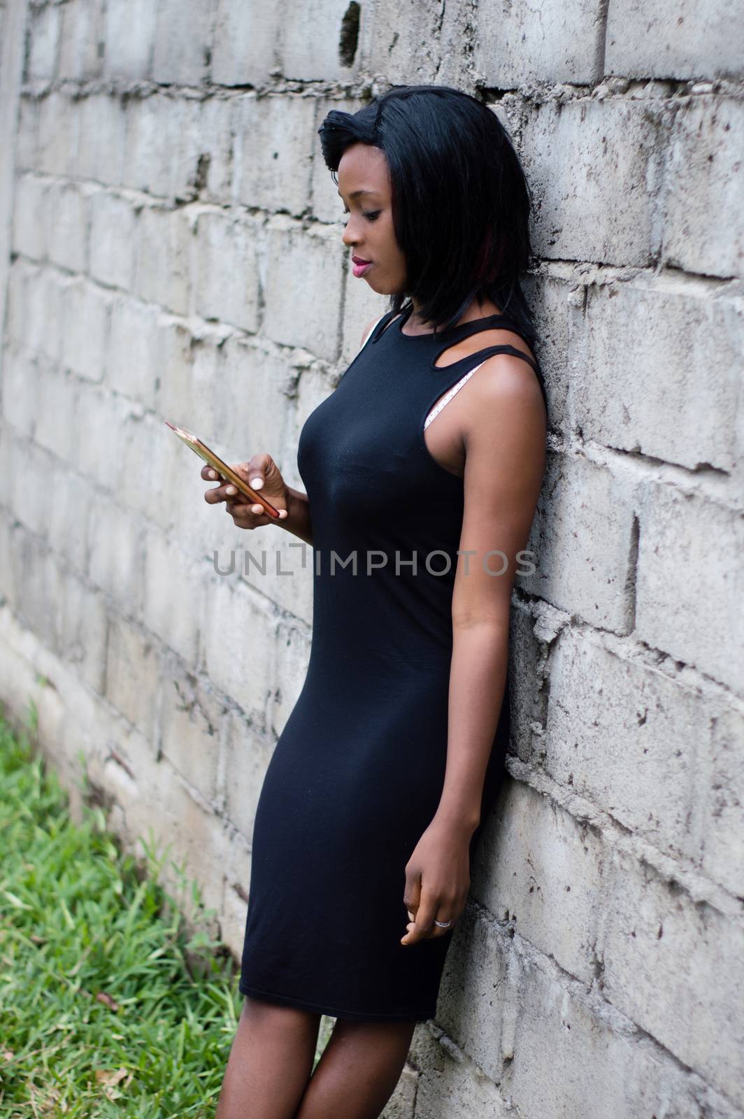 Young woman using a phone against the wall